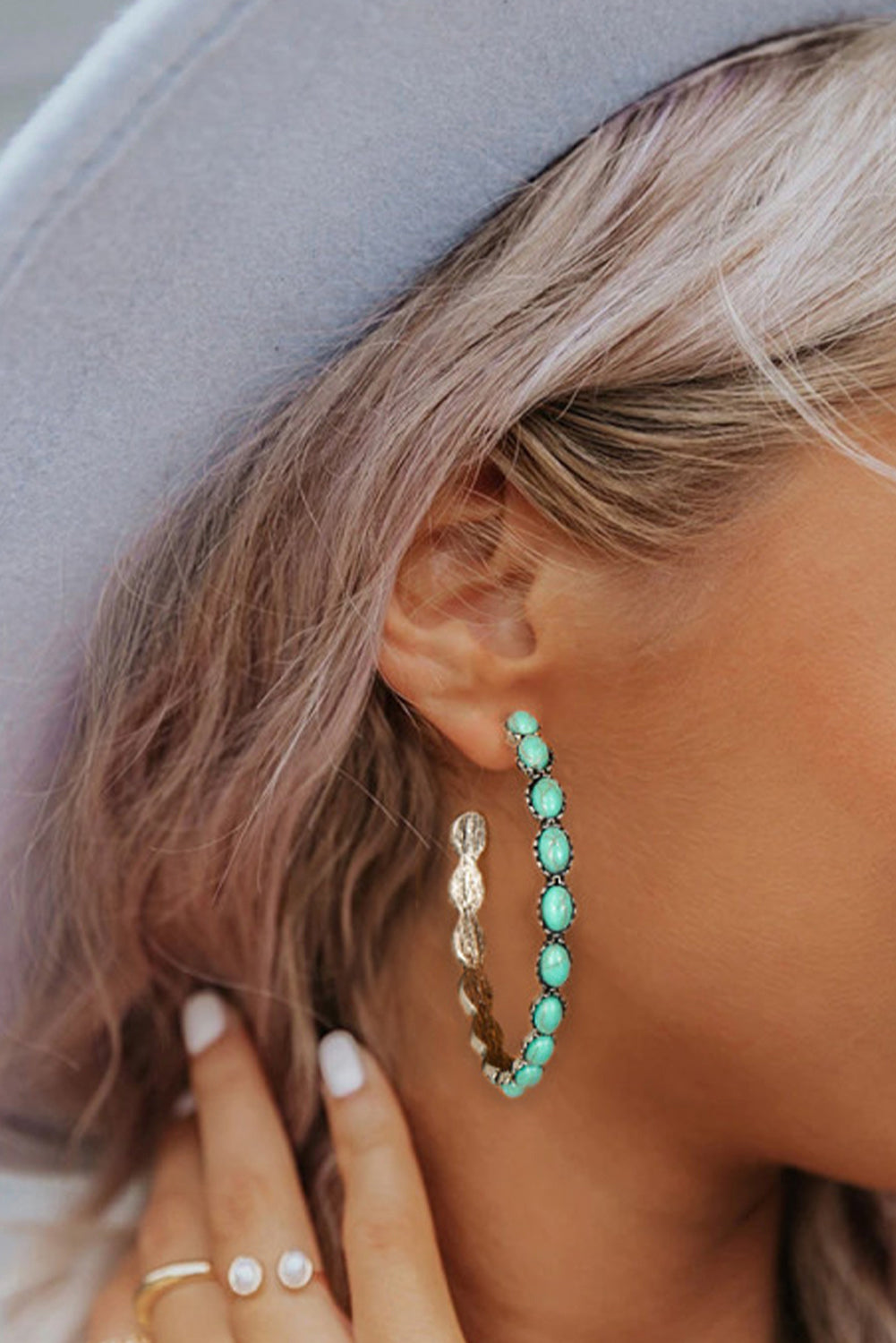 Turquoise beaded hoop earring on a woman's ear.