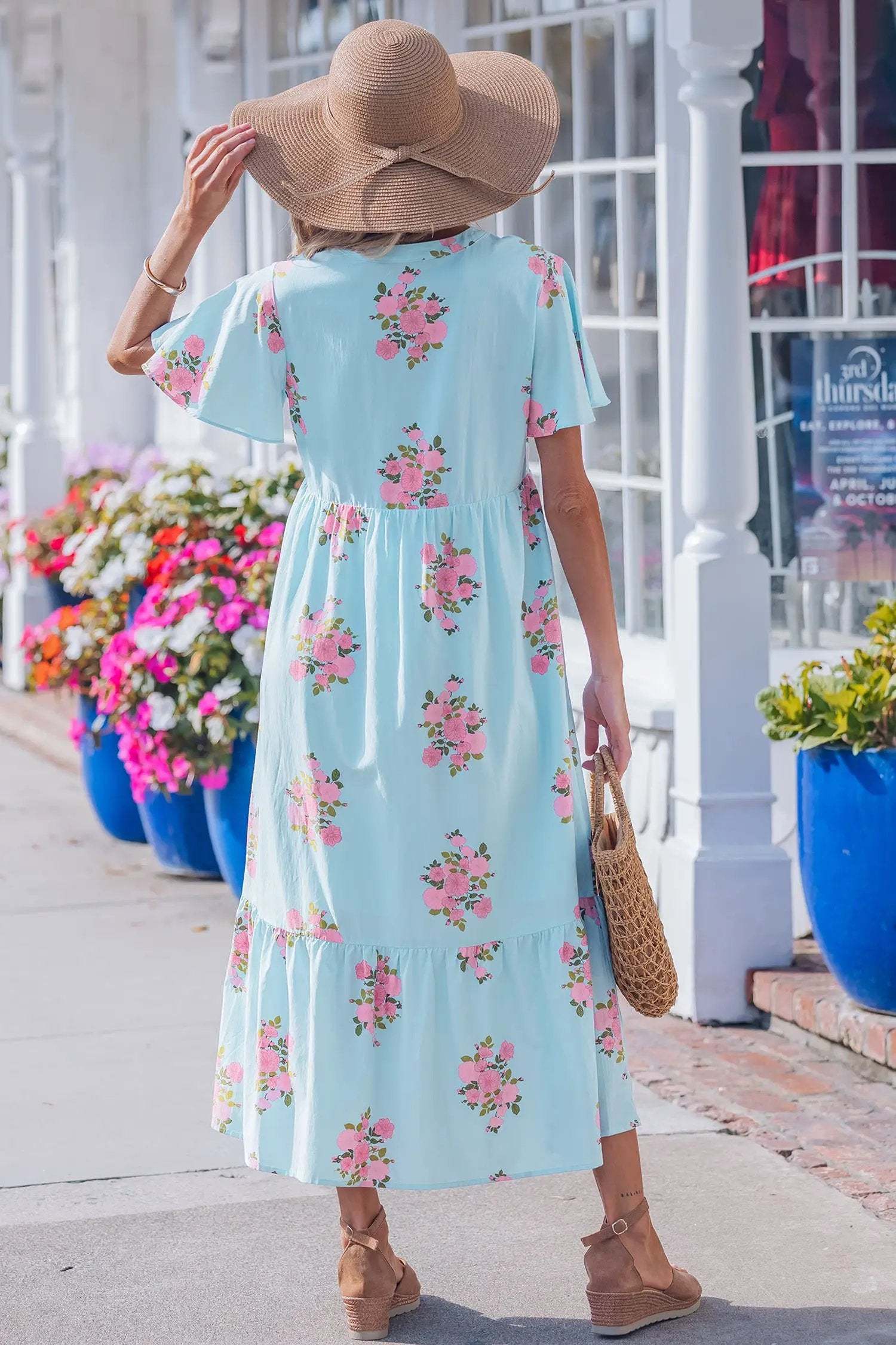 woman wearing pink floral maxi dress with notched neck and flutter sleeves outdoors