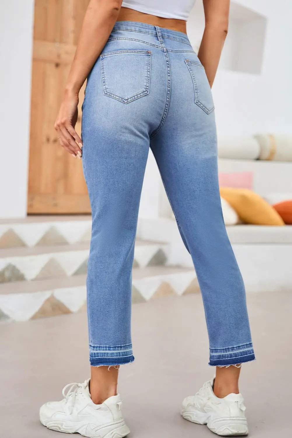 Woman wearing whiskered wash cropped jeans with raw hem showcasing main character energy style