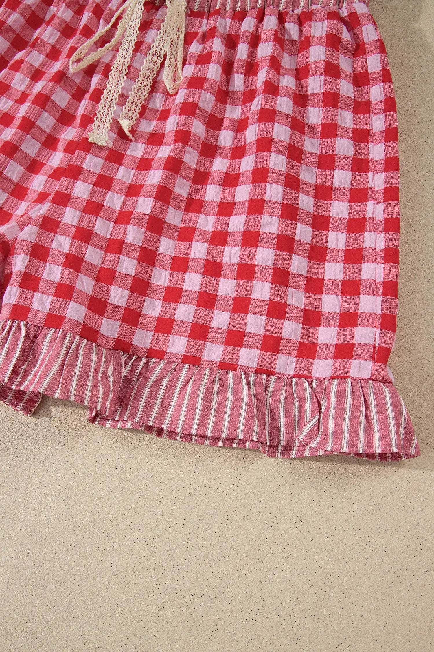 Woman wearing gingham ruffle hem shorts with lace tie waist sitting on steps outdoors