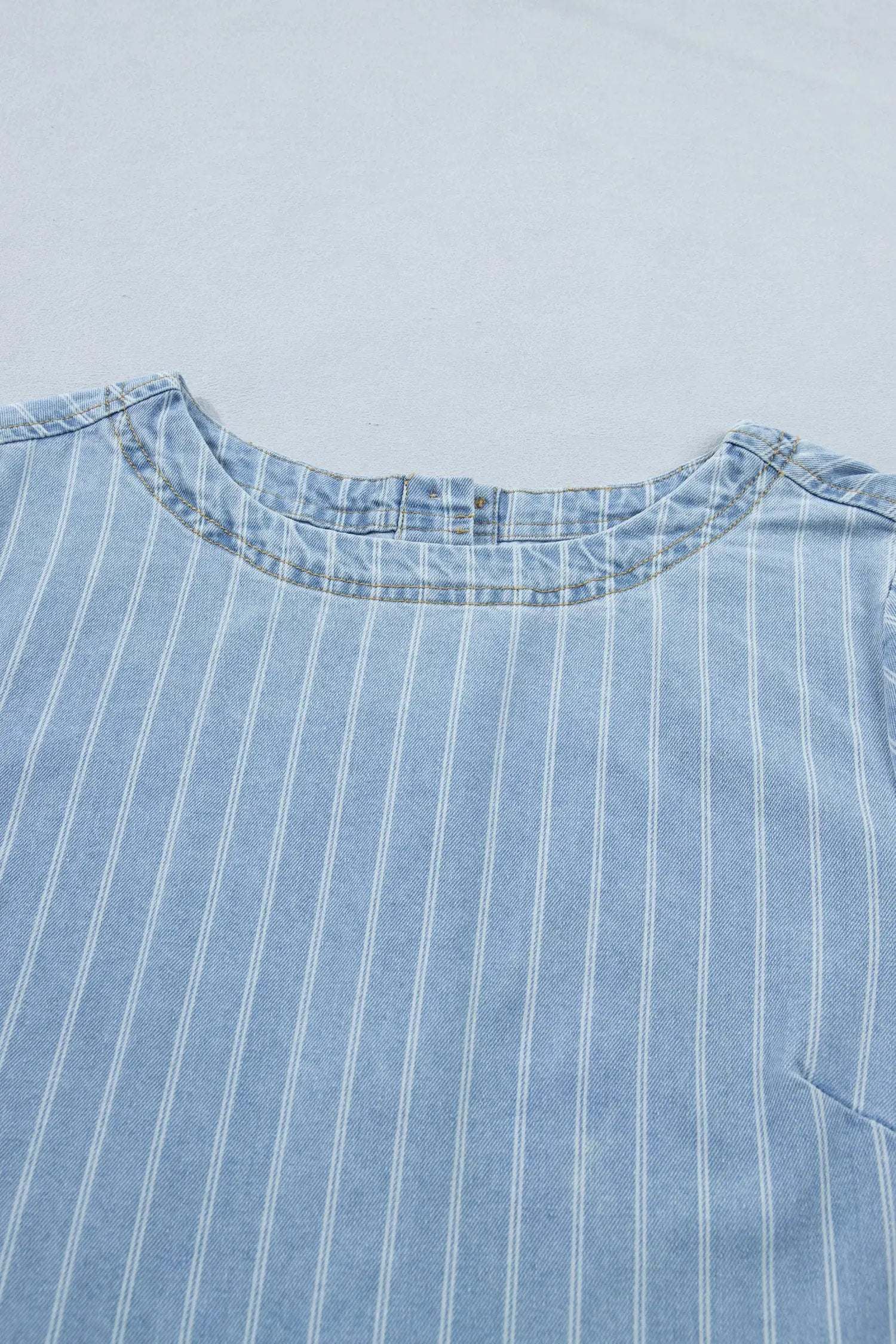 Woman wearing stripe denim mini dress with buttoned back outdoors