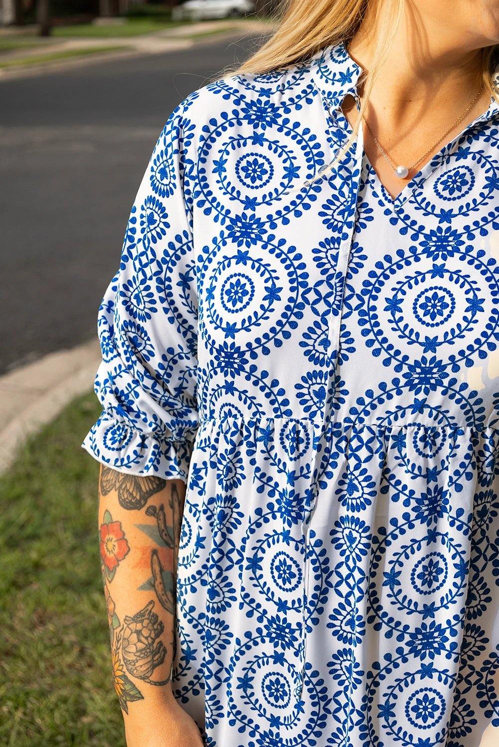 Plus size woman wearing blue and white geometric print maxi dress with lace-up notch neck standing outdoors