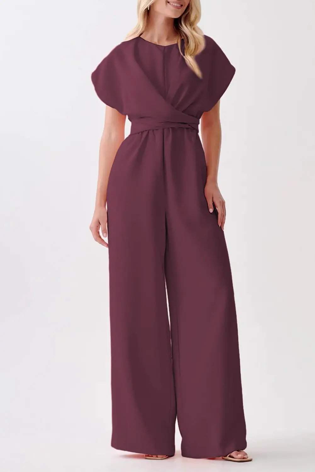 Woman wearing a rich wine knot-waist cap sleeve jumpsuit with wide-leg silhouette