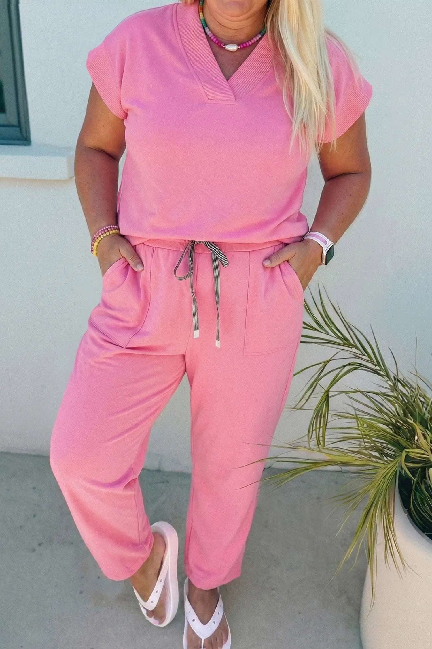Plus size woman wearing relaxed V-neck tee and drawstring pants outfit set sitting on chair with coffee cup