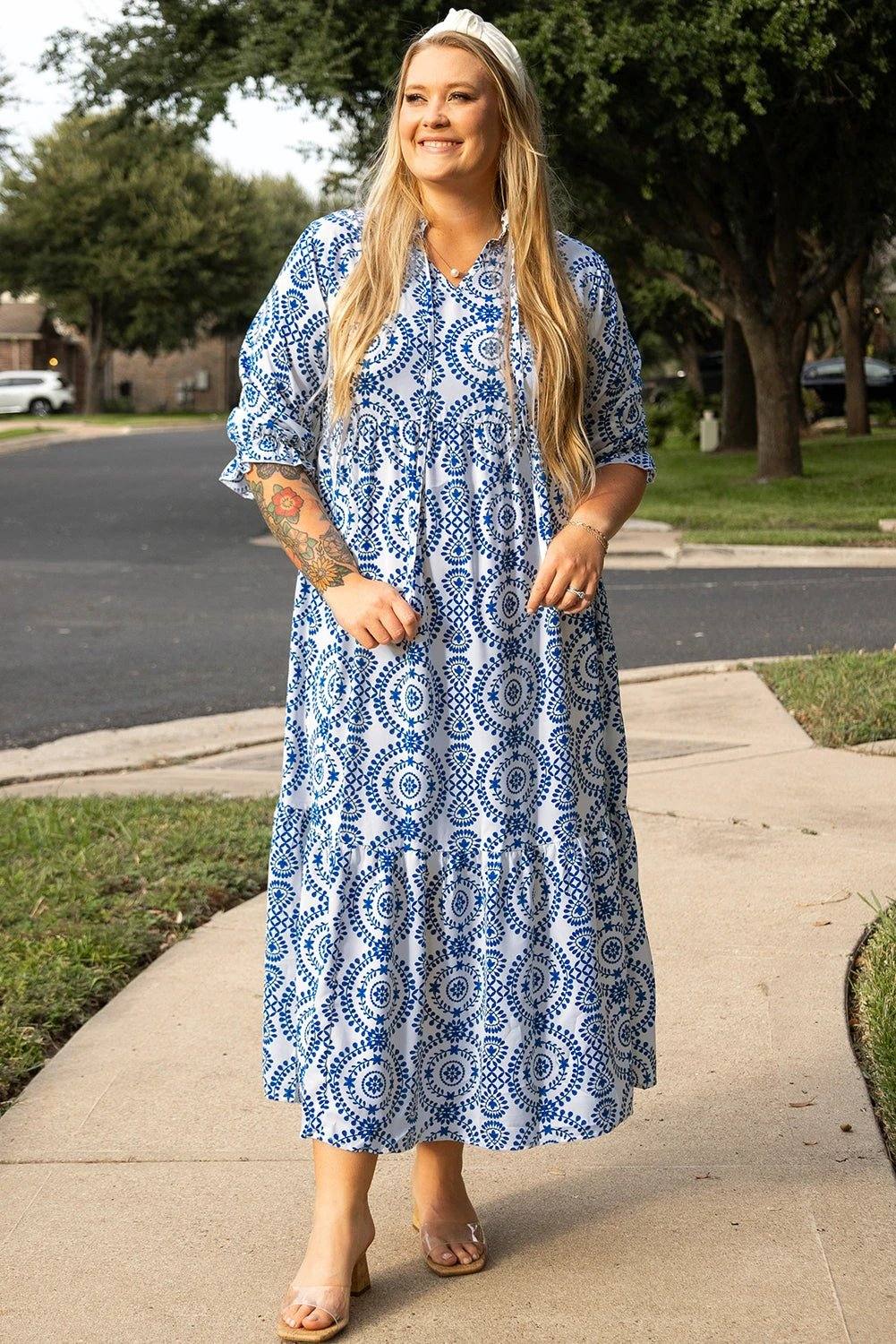 Plus size woman wearing blue and white geometric print maxi dress with lace-up notch neck standing outdoors