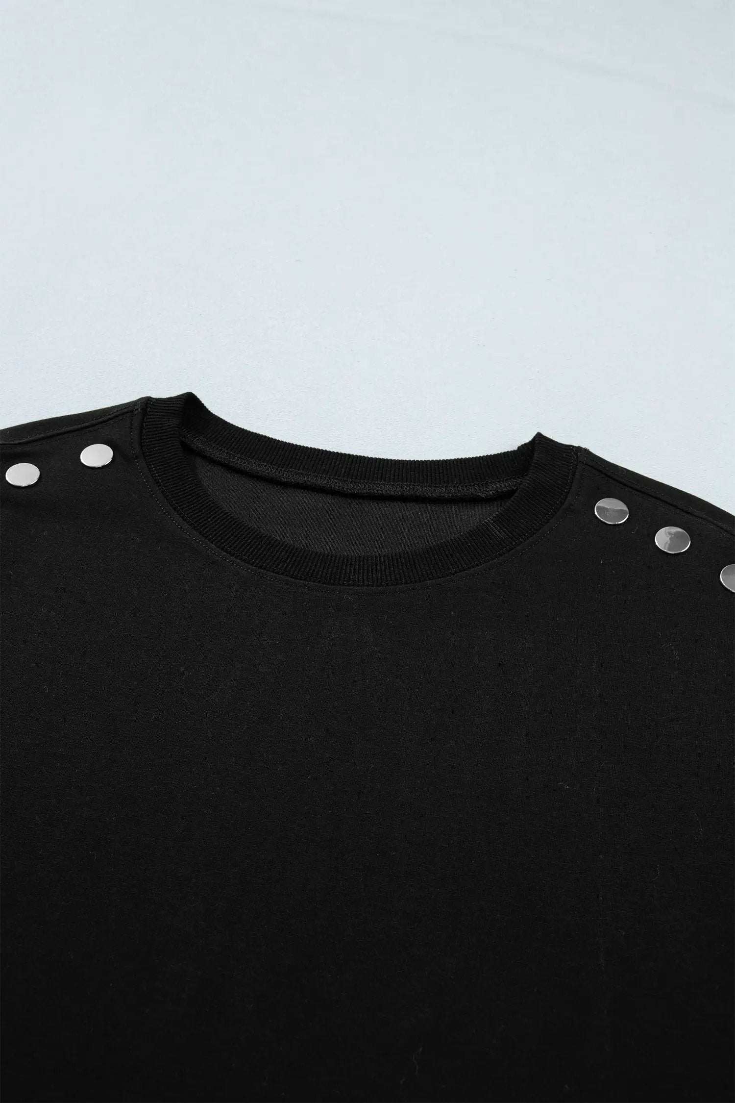 Woman wearing effortless chic mom short sleeve top with metal button details in black