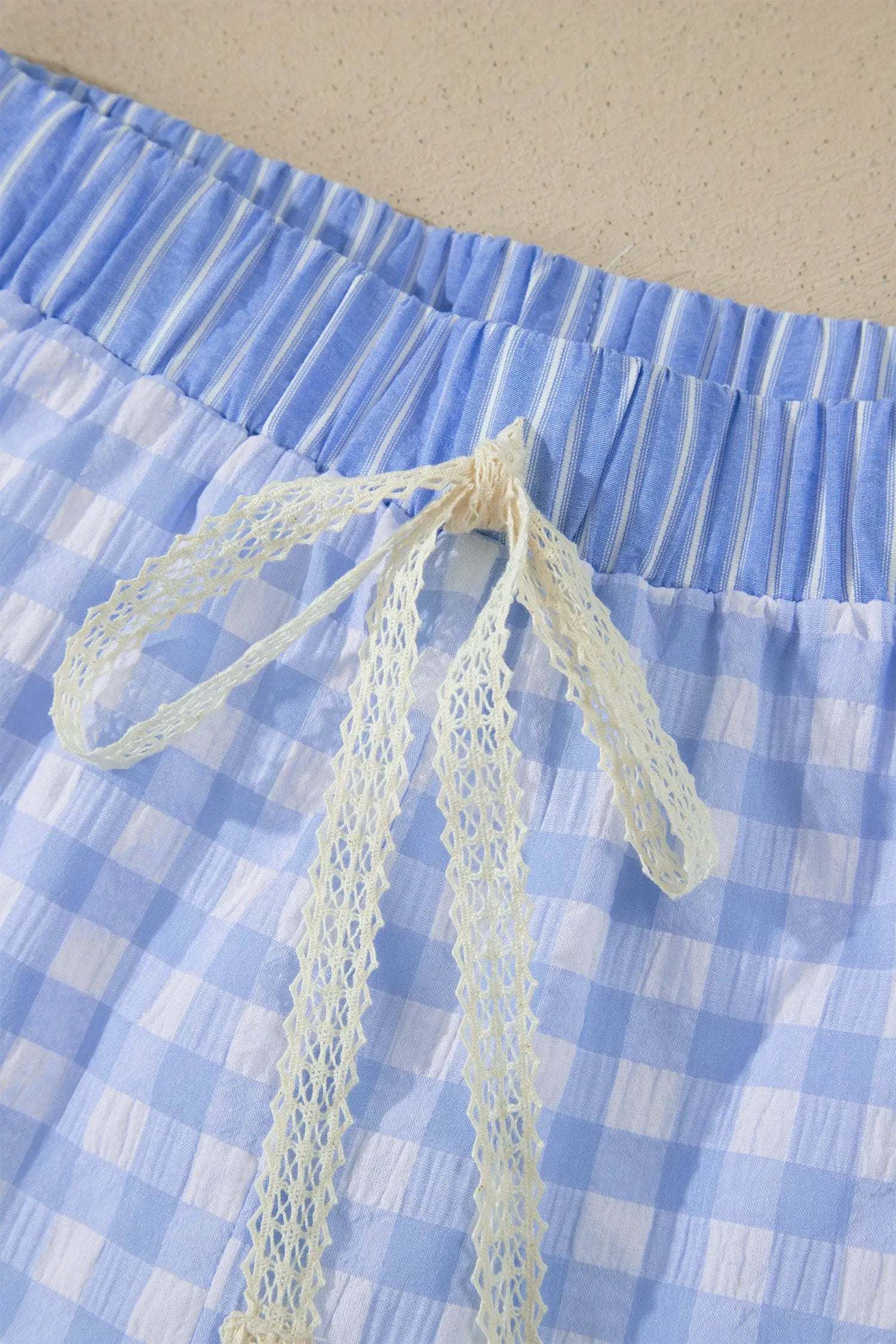 Woman wearing gingham ruffle hem shorts with lace tie waist in casual outdoor setting