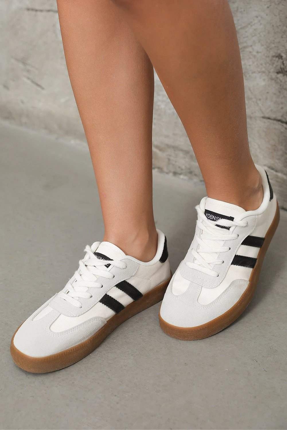 White striped lace-up flat sneakers with black accents for chic mom energy style