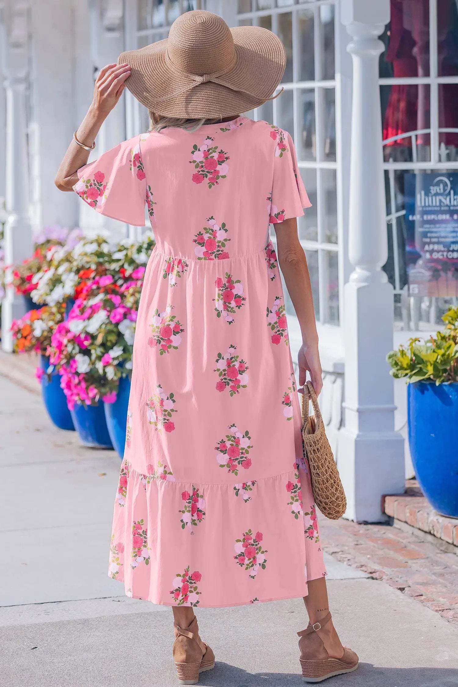 woman wearing pink floral maxi dress with notched neck and flutter sleeves