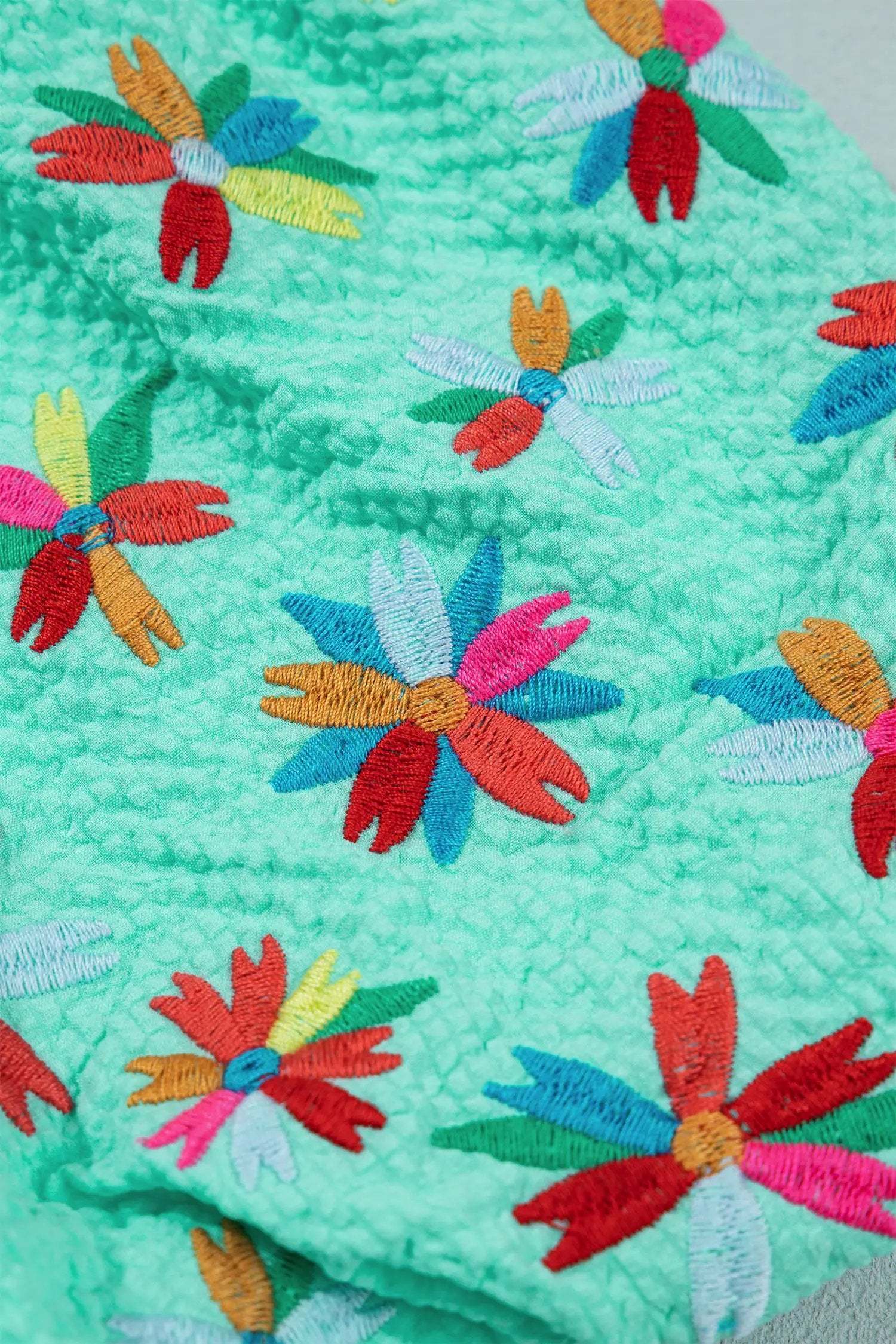 V-neck floral embroidered blouse with puff sleeves and frill edges on white background