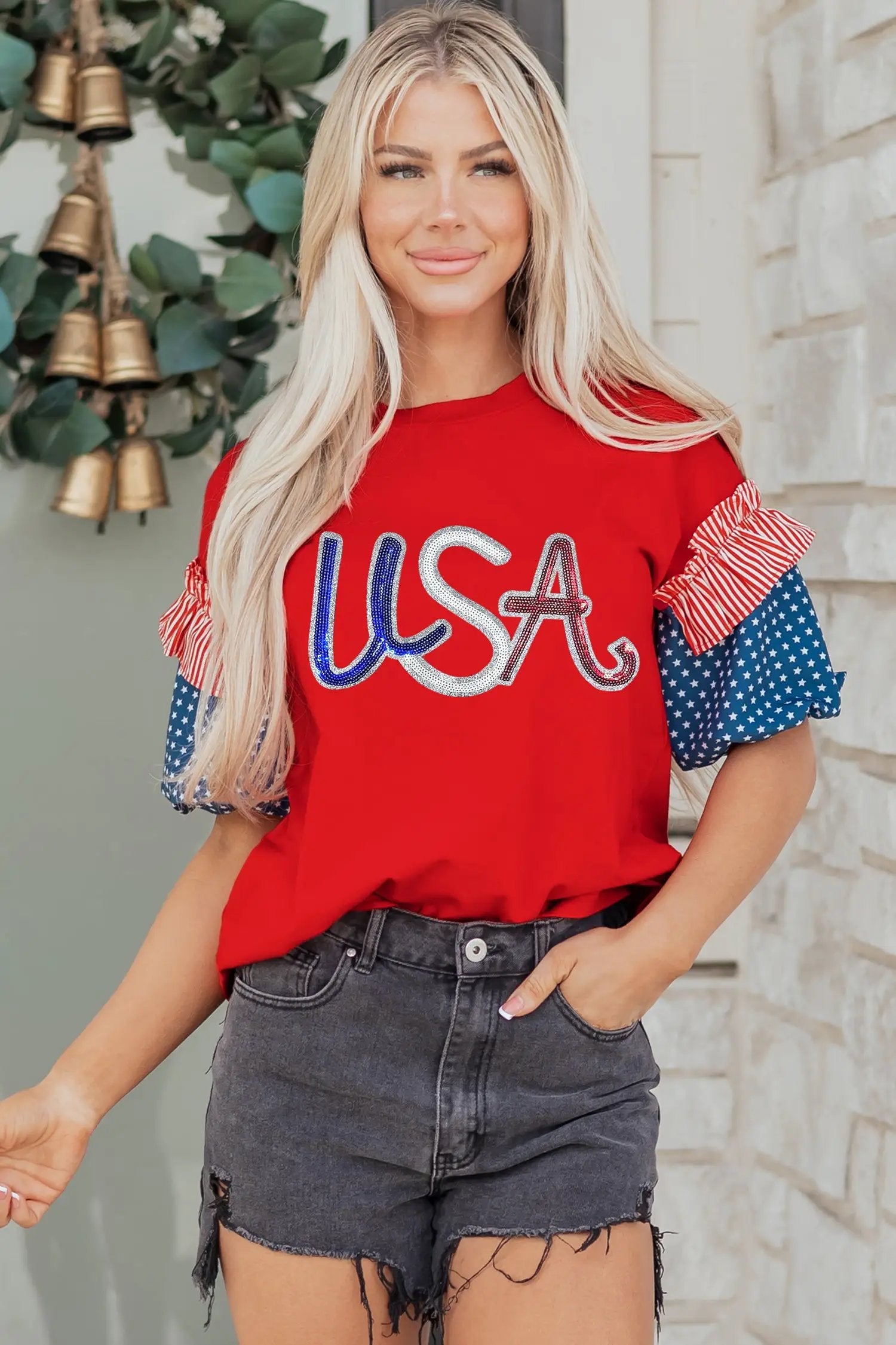 Woman wearing a fiery red sequin USA graphic tee with contrast spliced starry blue and striped sleeves