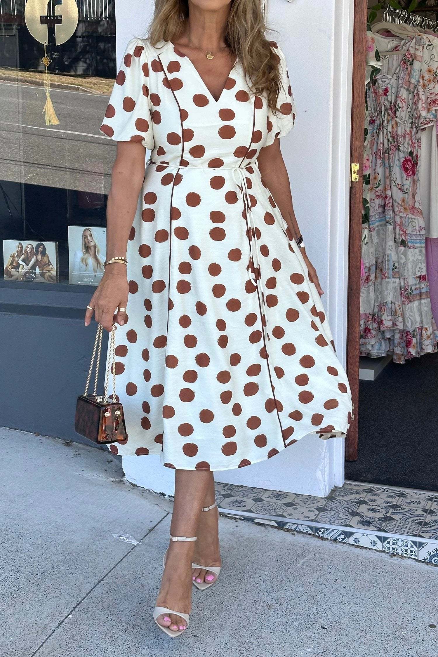 White midi dress with warm brown polka dots, V-neck, short sleeves, and tie waist design