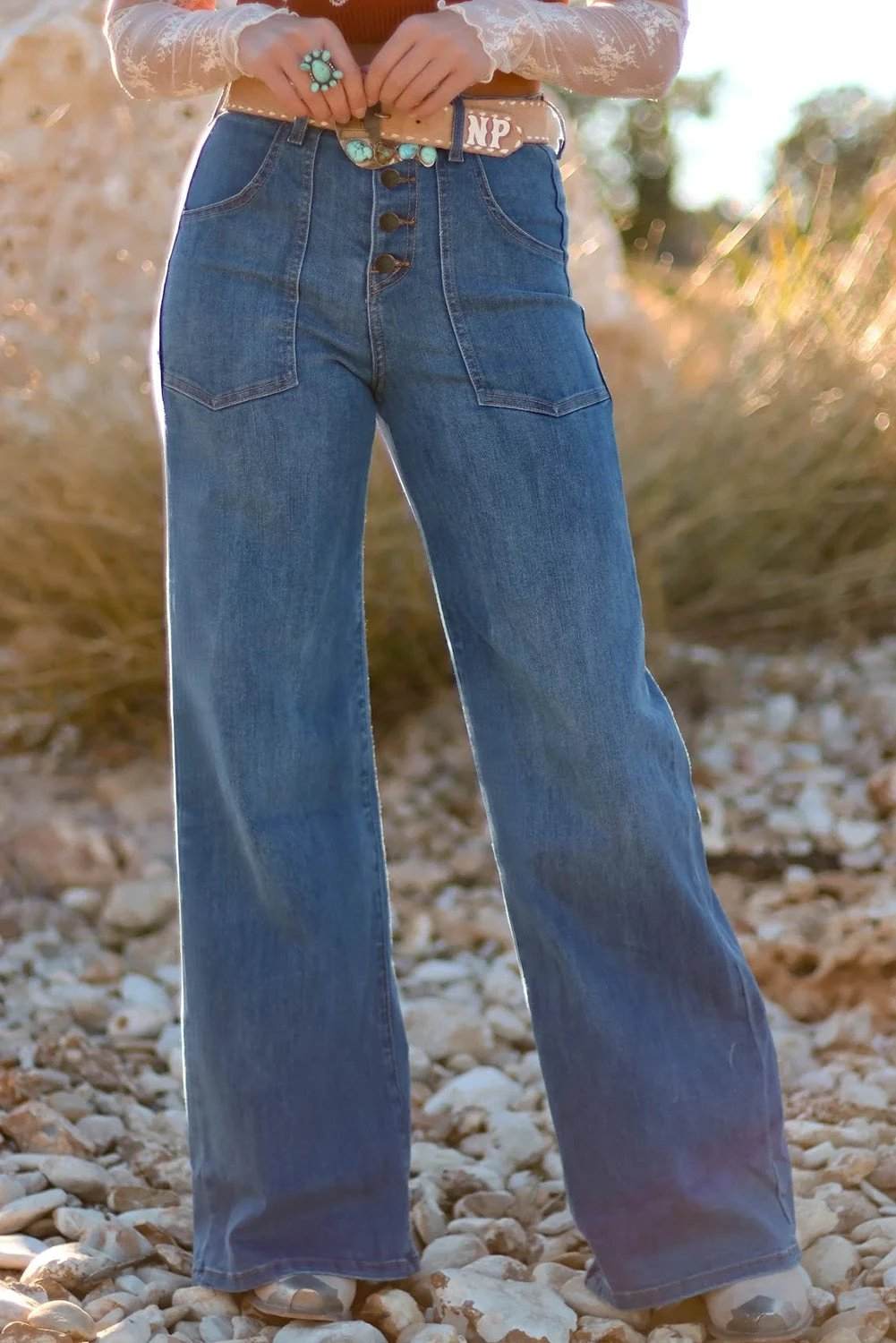 Woman wearing button-front high-waisted wide-leg jeans with pockets standing outdoors