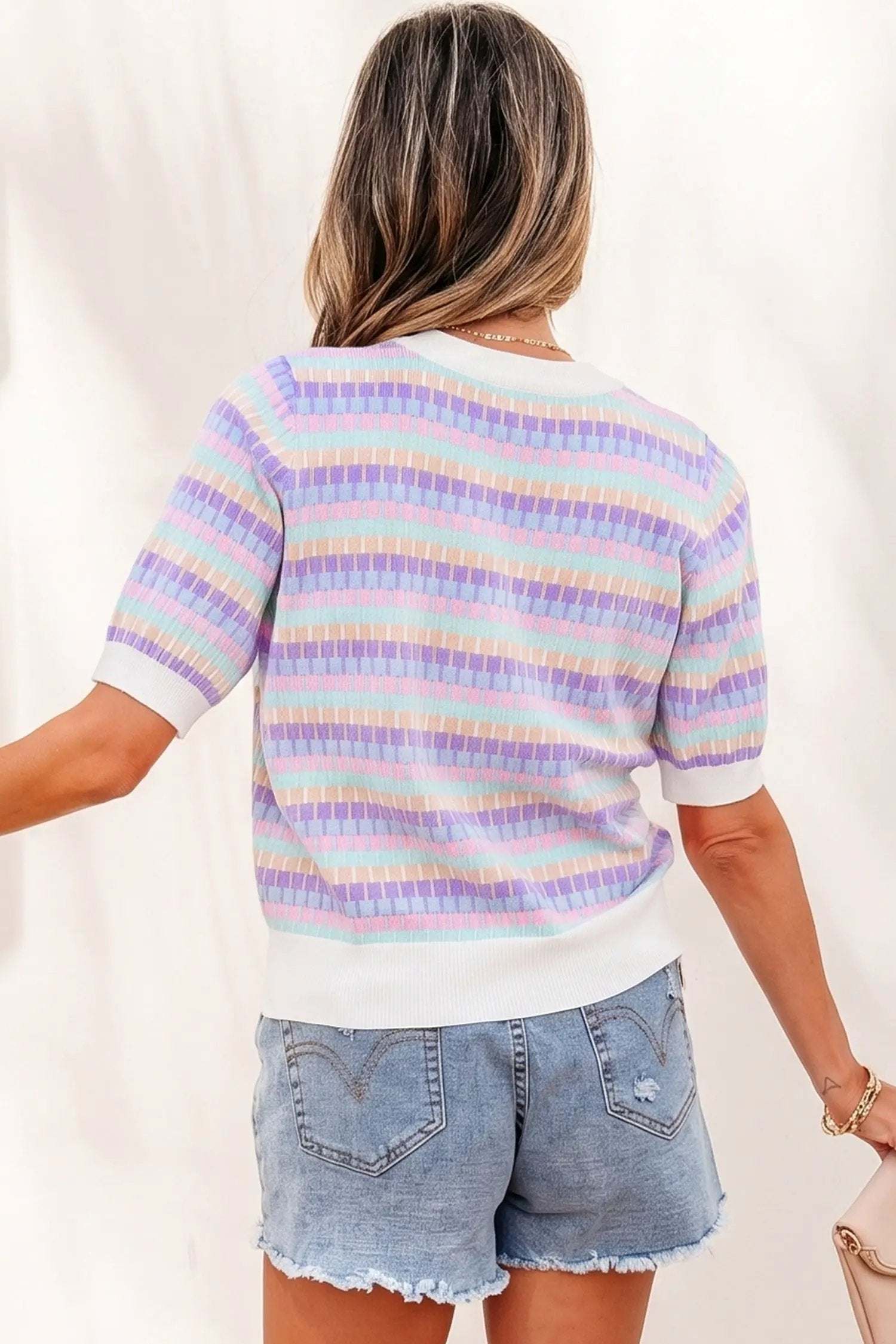 Woman wearing orange striped knit sweater with short sleeves and fuchsia pink ribbing