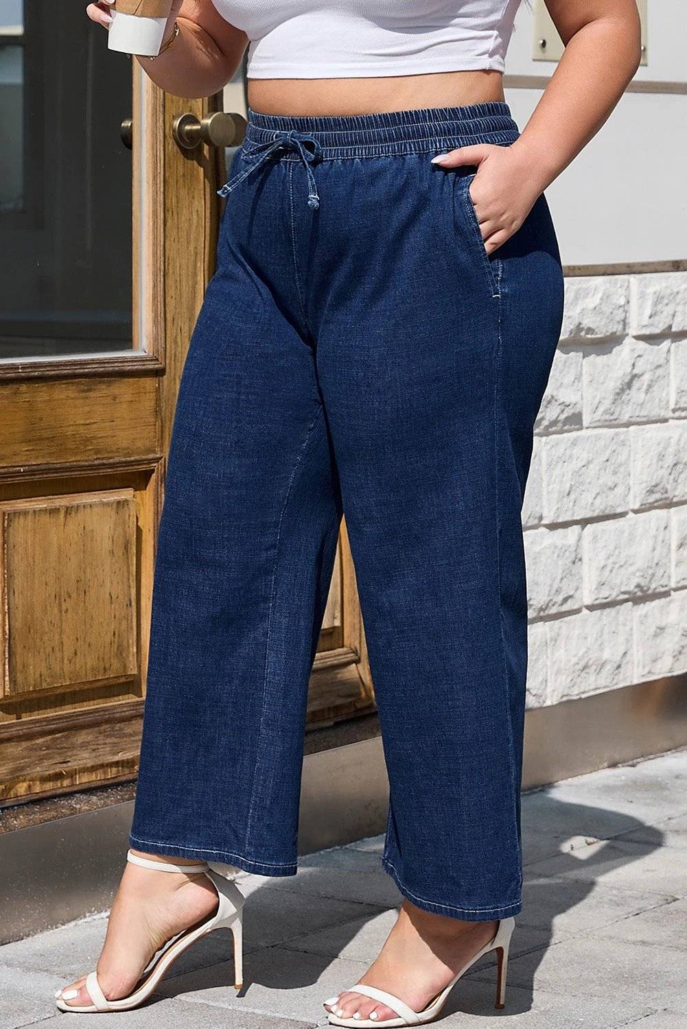 Plus size model wearing indigo drawstring high waist wide leg jeans