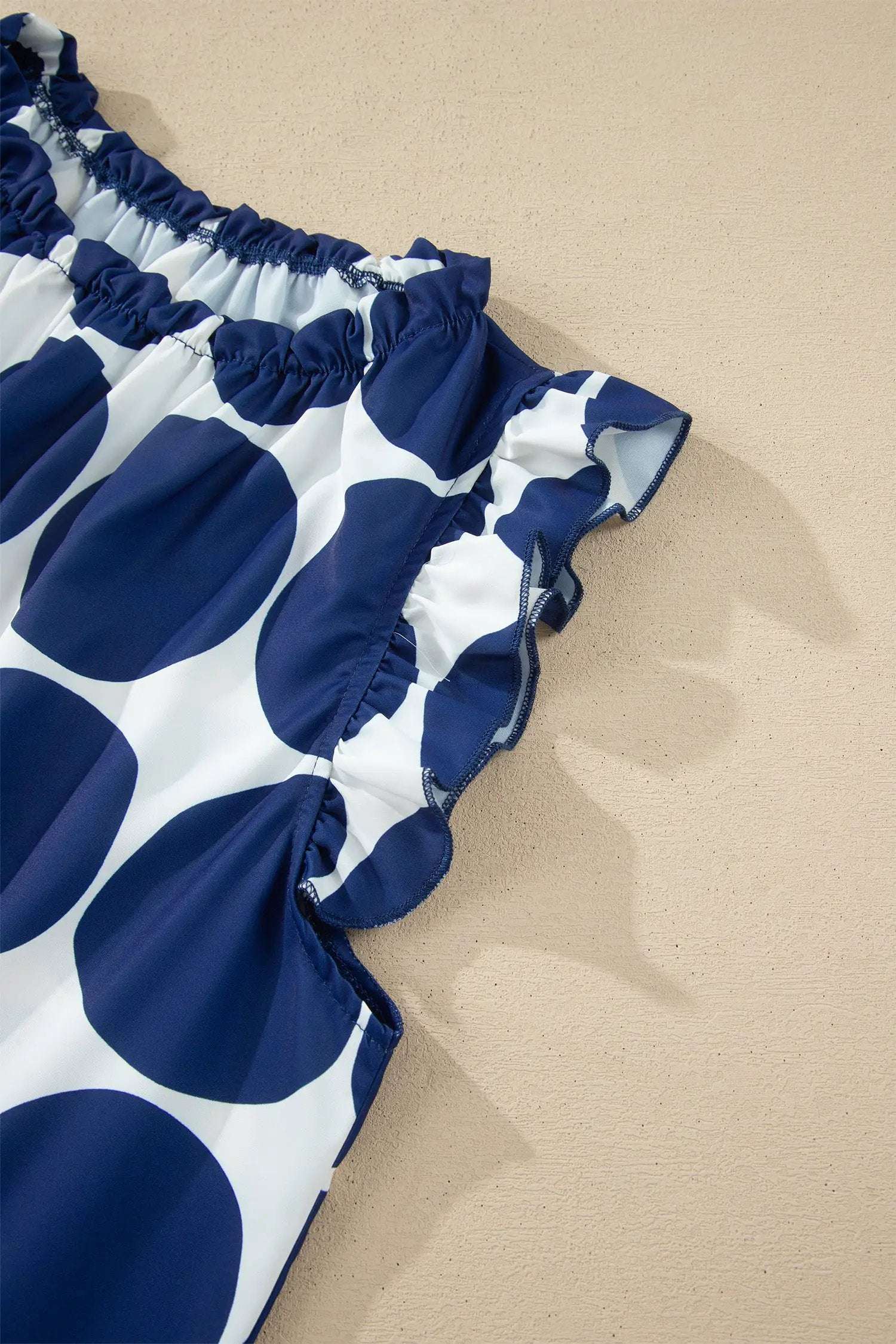 Blue and white polka dot tank top with frilled round-neck and shoulder ruffles on lightweight fabric