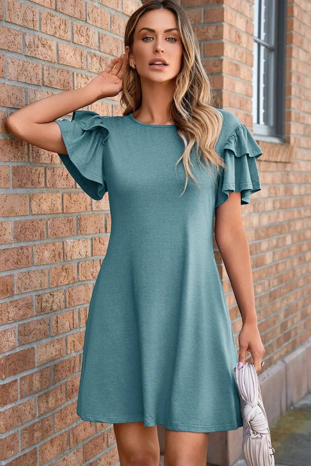 Woman wearing a round neck double-ruffle mini dress with short flutter sleeves, styled for casual confidence