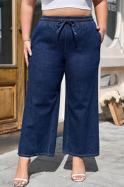 Plus size model wearing indigo drawstring high waist wide leg jeans