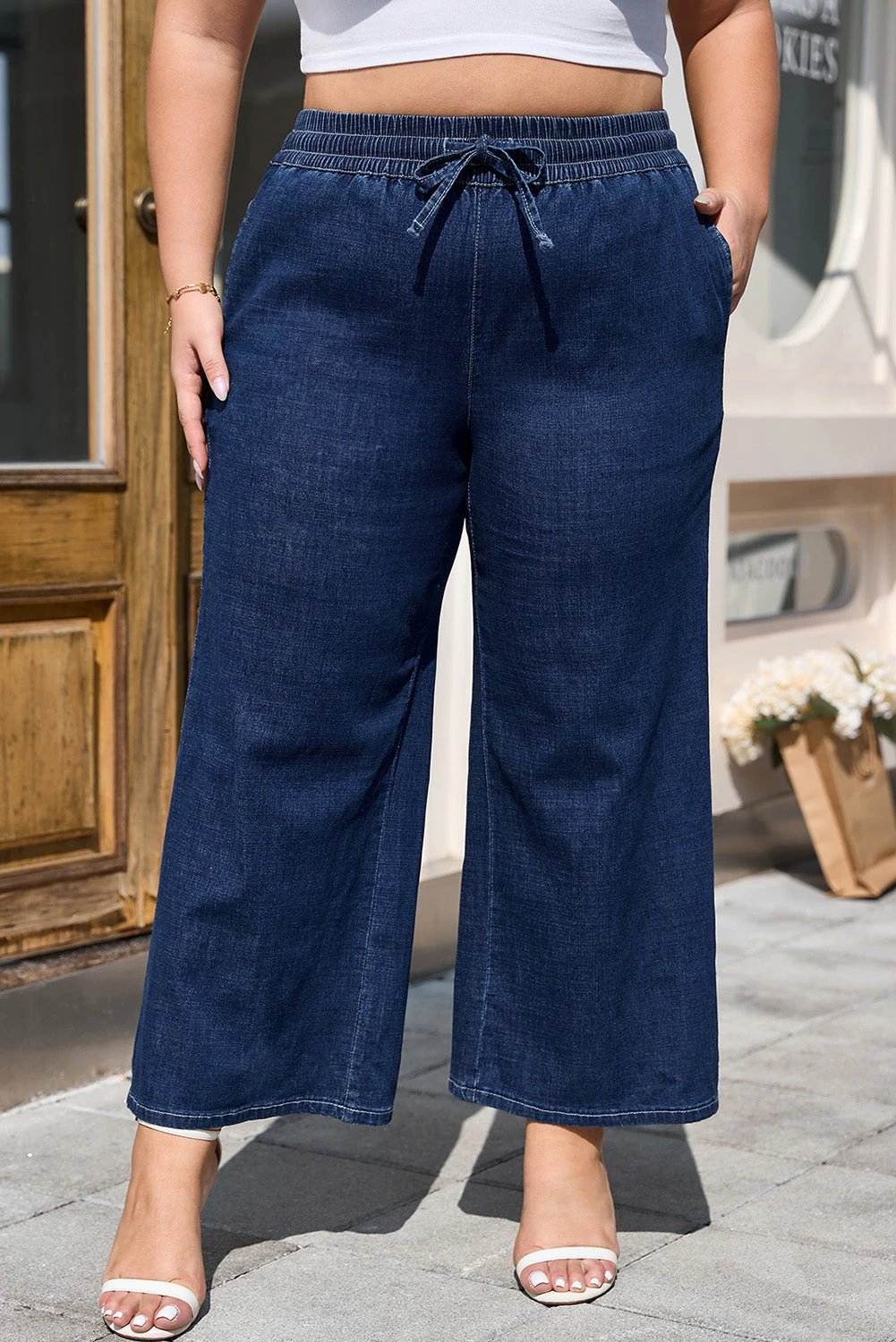 Plus size model wearing indigo drawstring high waist wide leg jeans