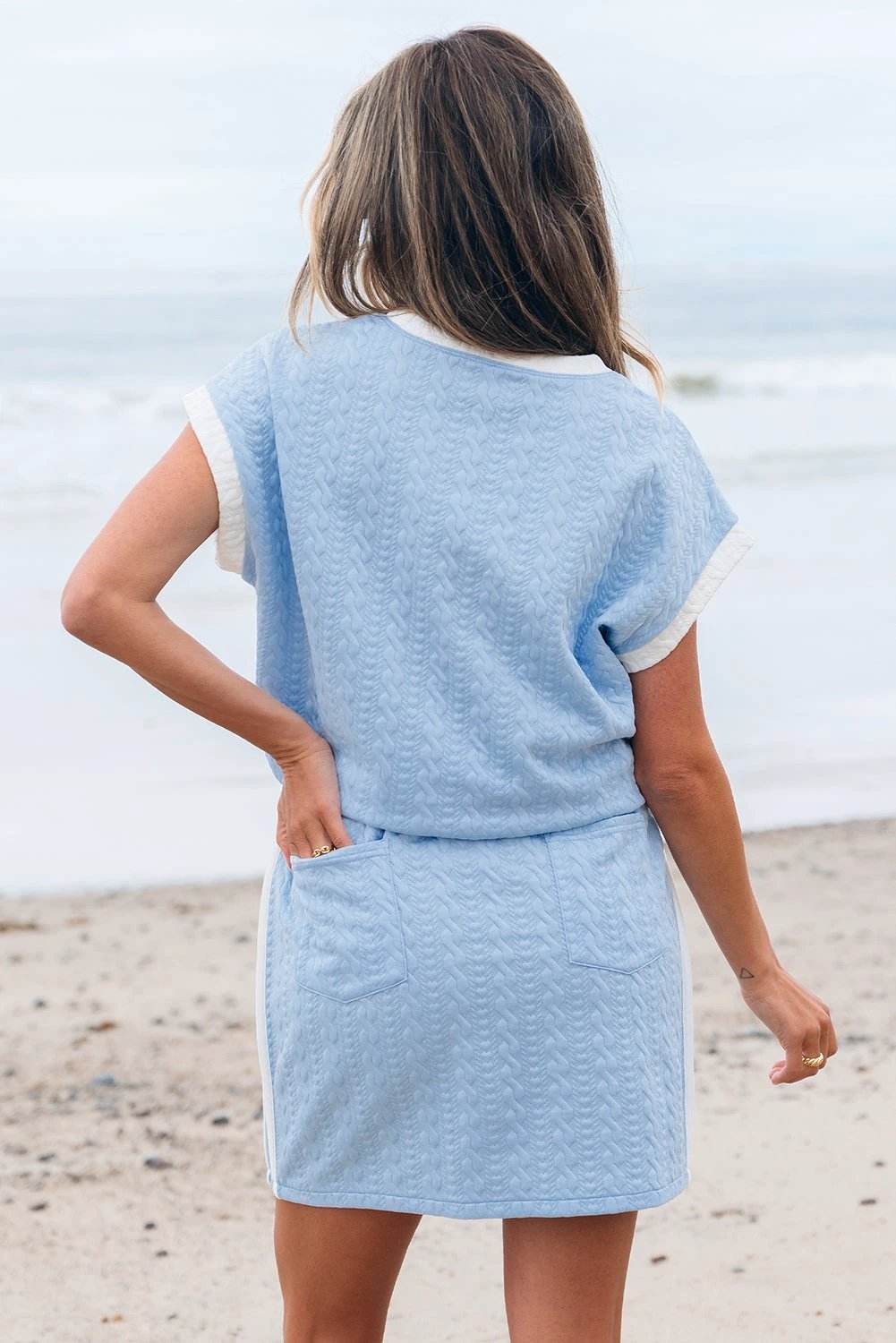 Soft blue textured crewneck tee with contrast white sleeve trim paired with pocketed skirt featuring side stripe for casual polished look