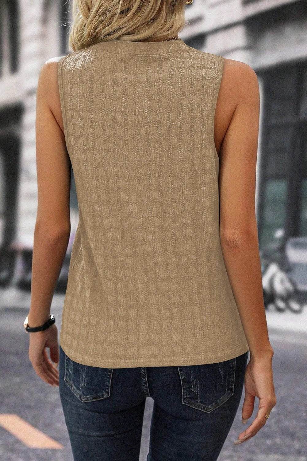 Woman wearing a lattice textured split-neck tank top paired with denim shorts