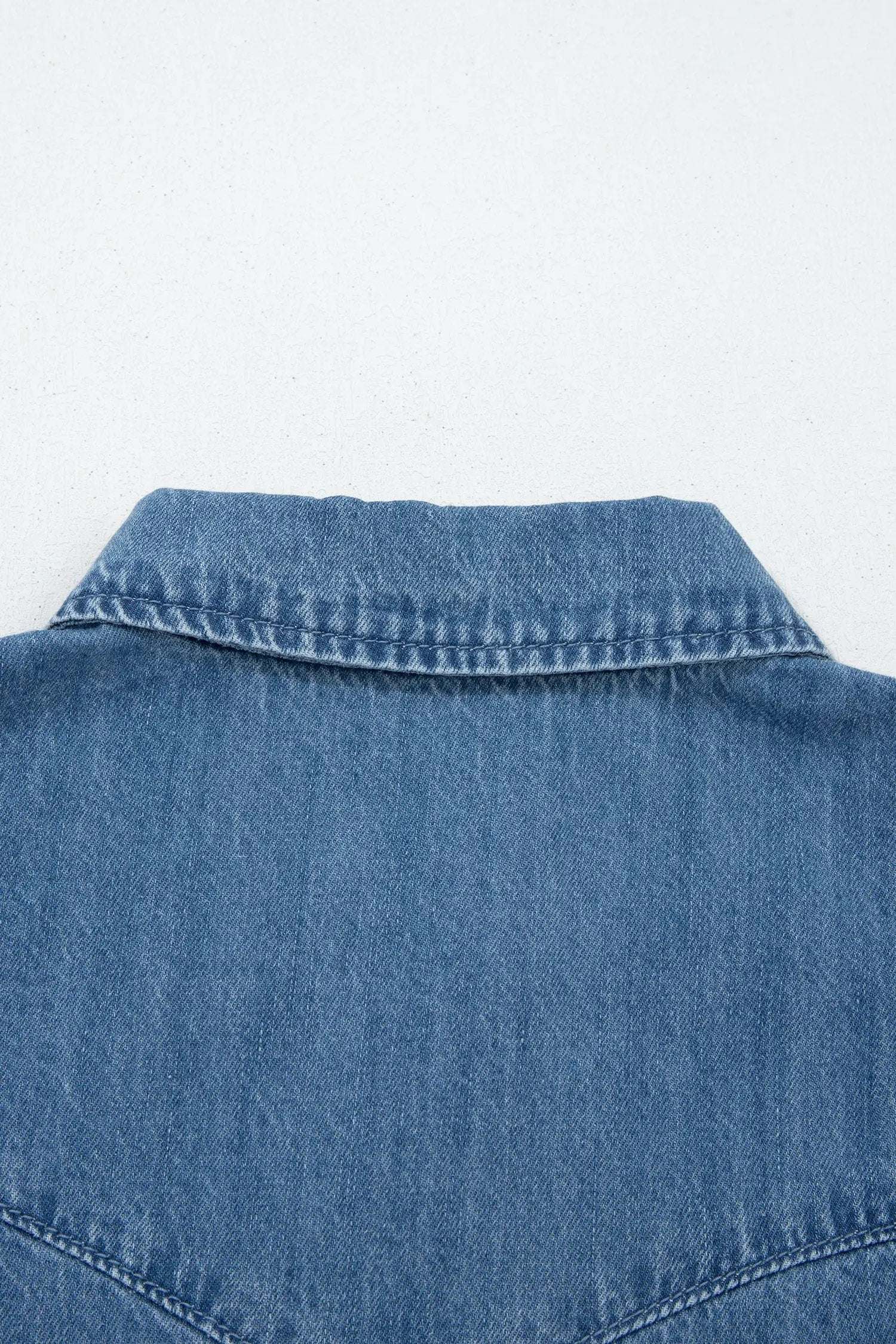 Woman wearing denim ruffled short sleeve shirt with button front and flutter sleeves