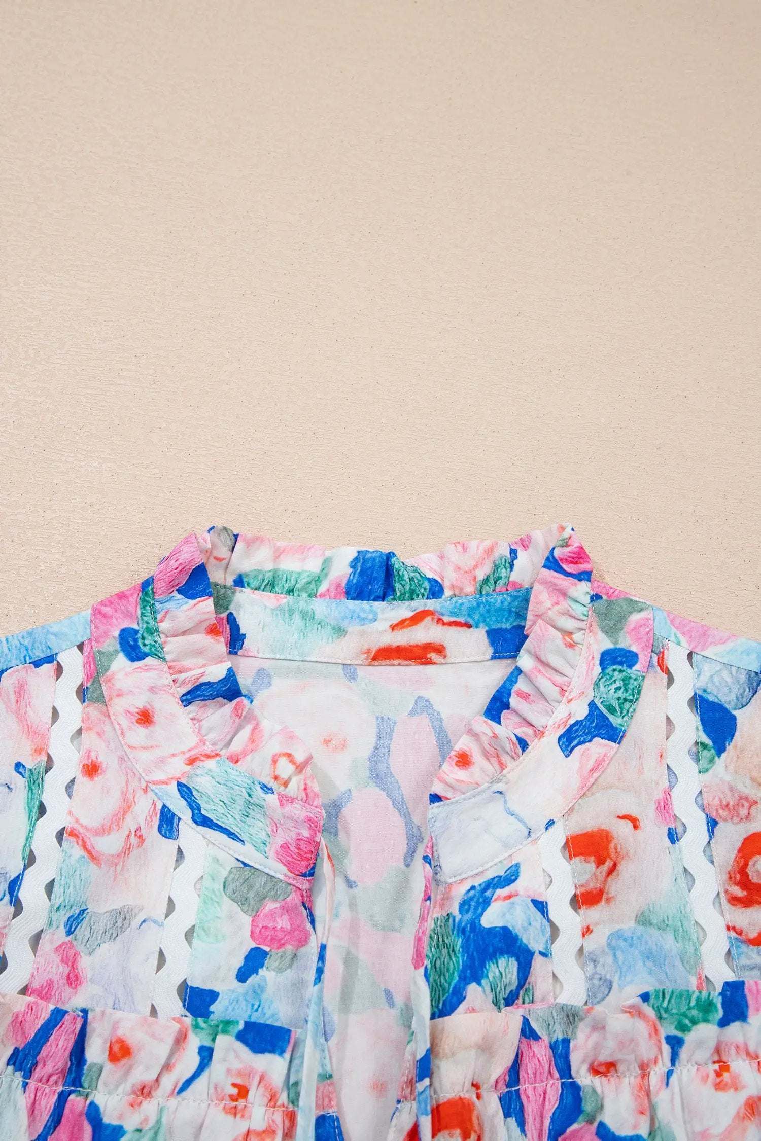 Woman wearing a Vacation Vibe floral tie-neck blouse with V-neck and ruffle short sleeves