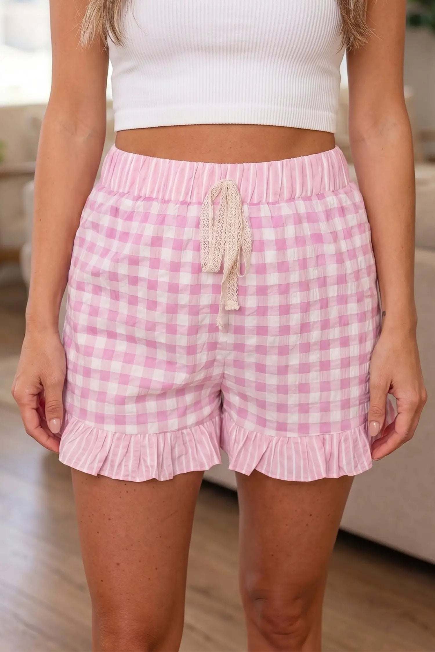 Woman wearing gingham ruffle hem shorts with lace tie waist for casual weekend style