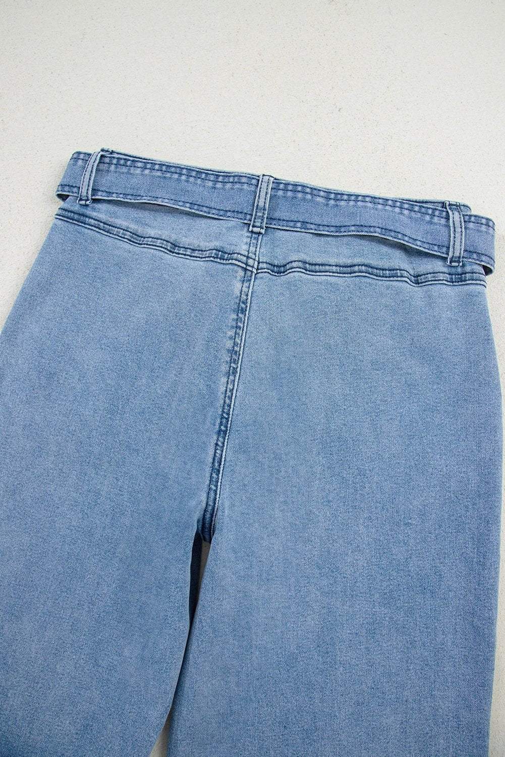 Woman wearing acid washed bow knot sash wide leg jeans standing indoors