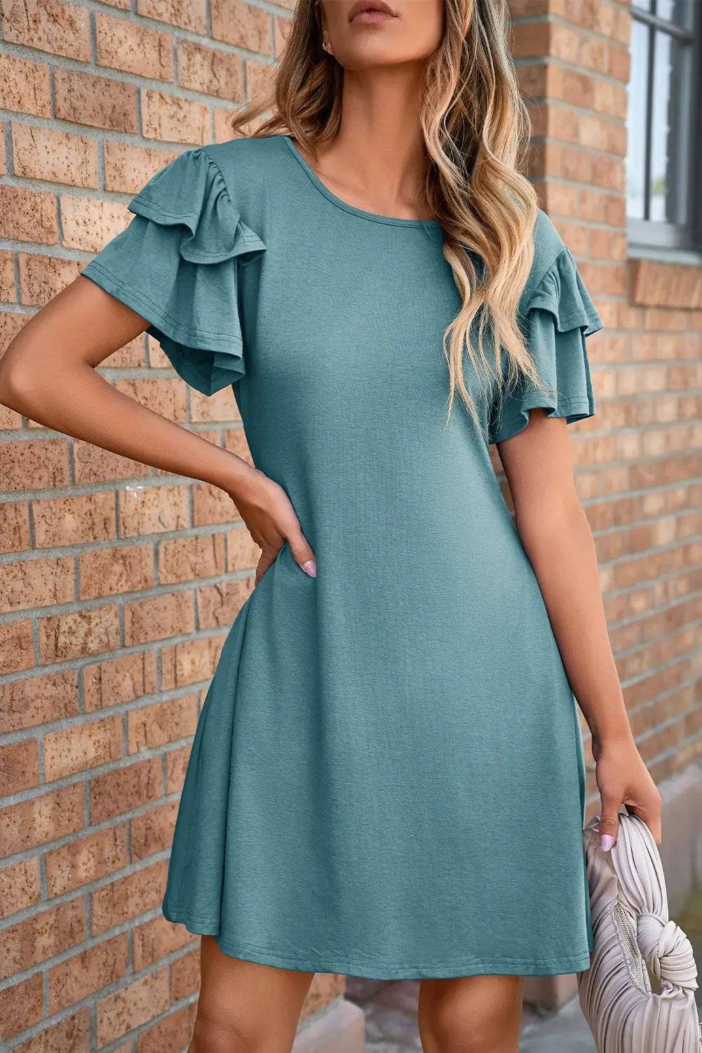 Woman wearing a round neck double-ruffle mini dress with short flutter sleeves in a casual setting