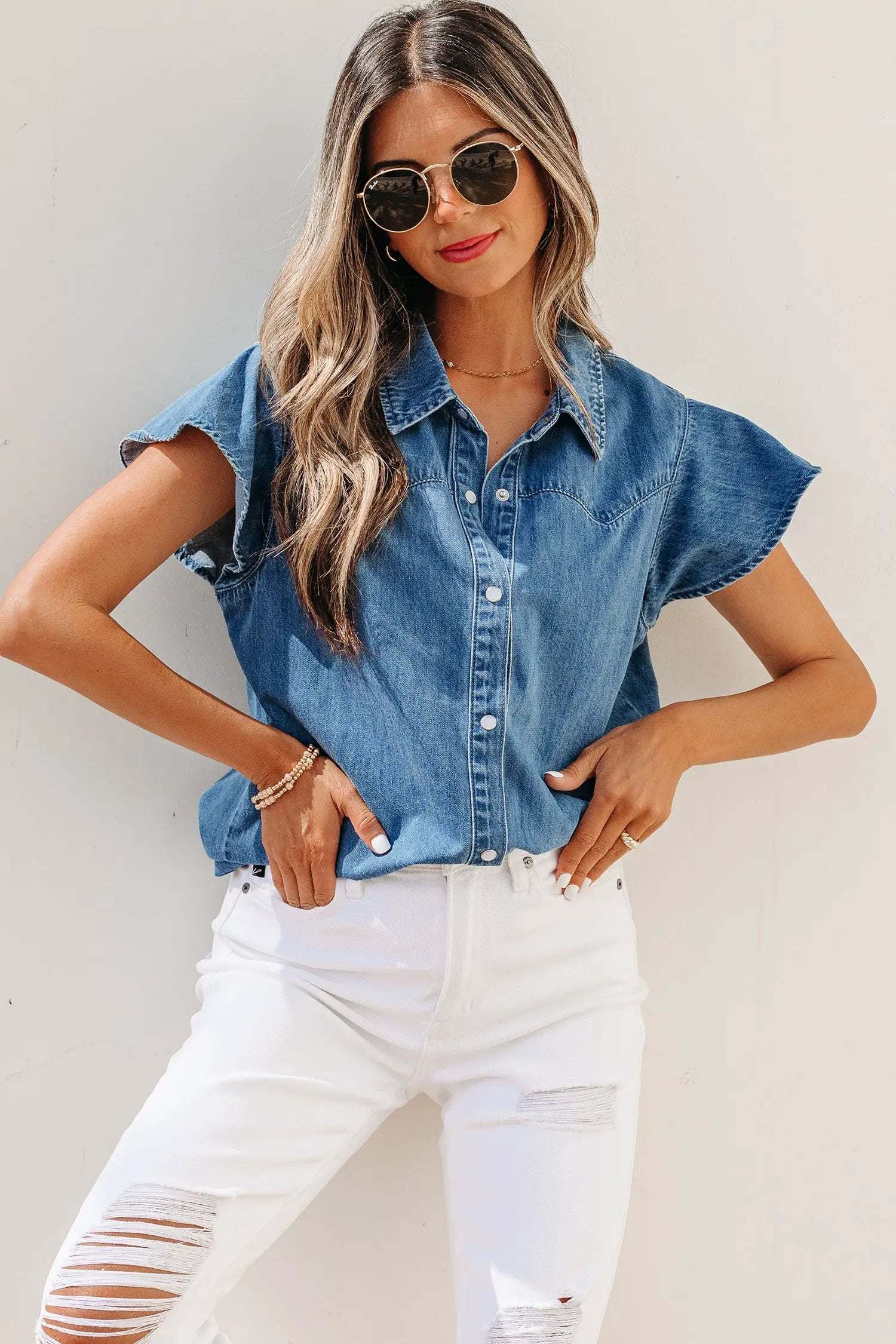 Woman wearing denim ruffled short sleeve shirt with button front and flutter sleeves