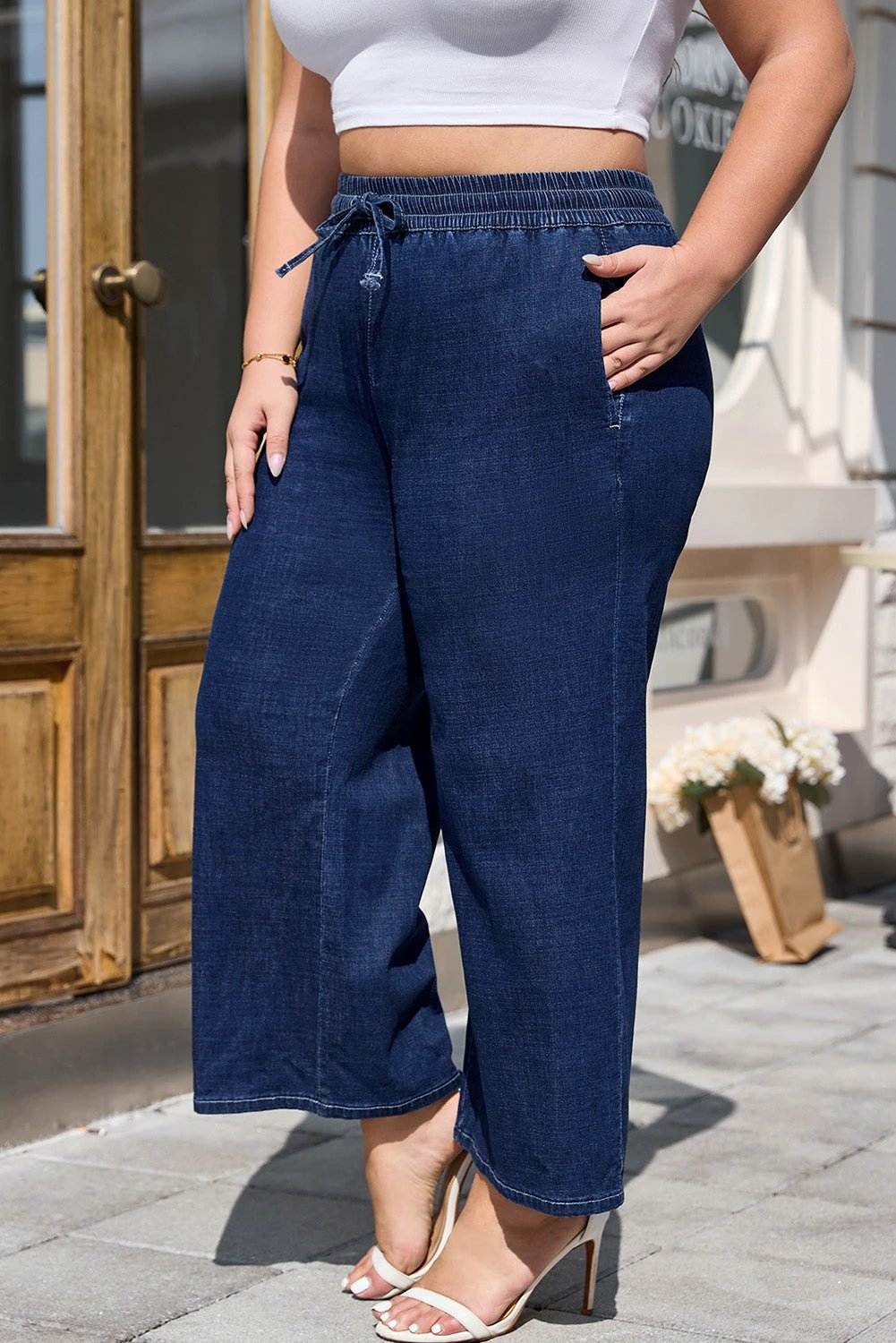 Plus size model wearing indigo drawstring high waist wide leg jeans