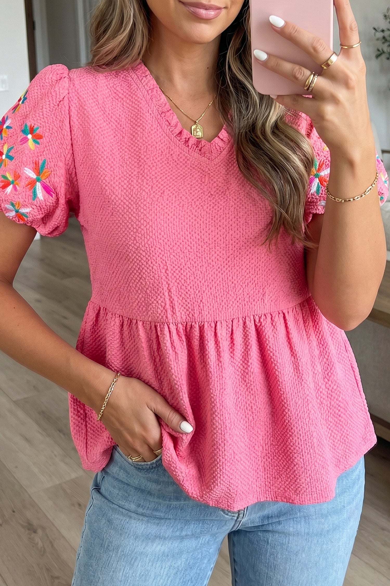 White floral embroidered blouse with V-neck and puff sleeves on wooden hanger