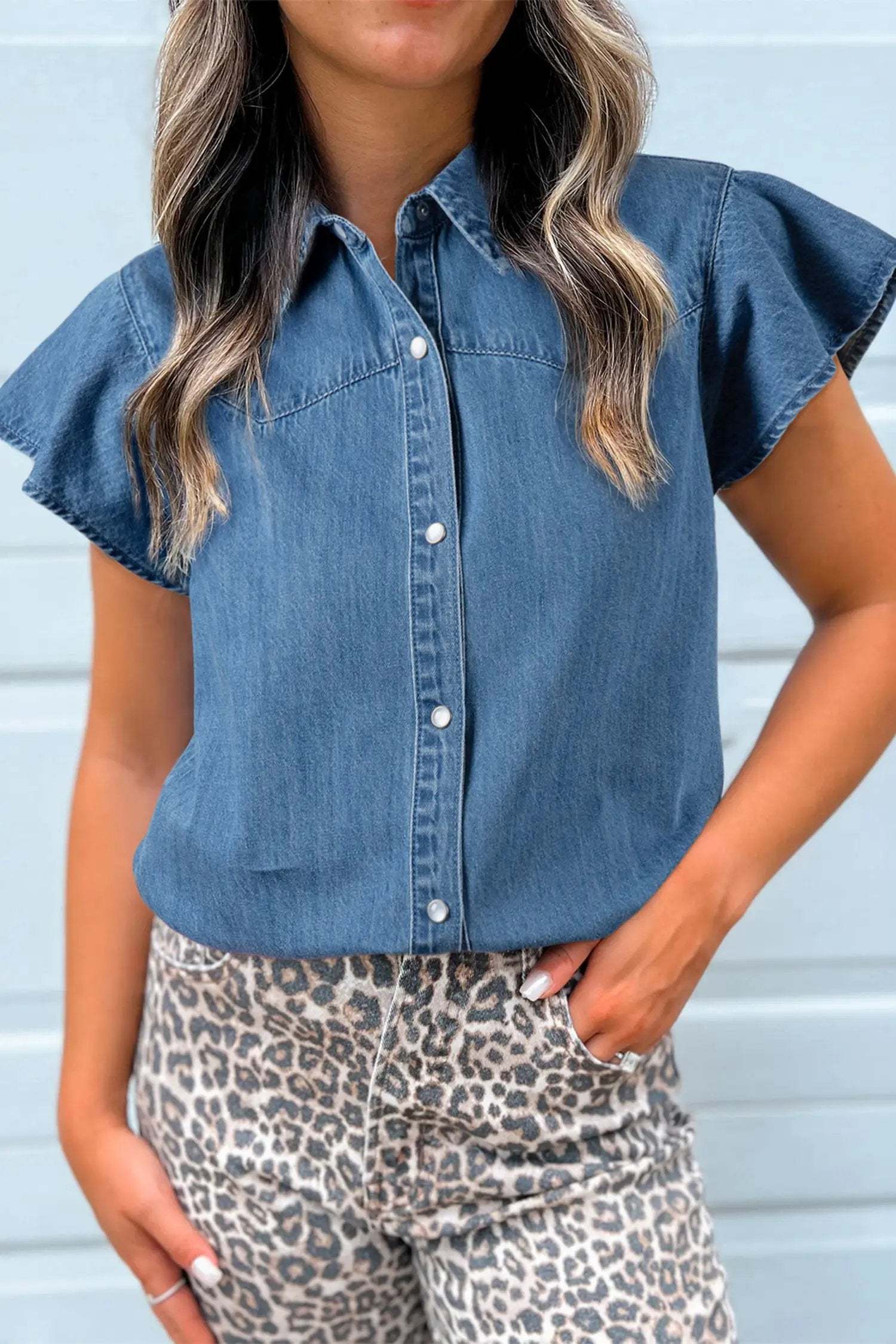 Woman wearing denim ruffled short sleeve shirt with button front in casual Western mom style