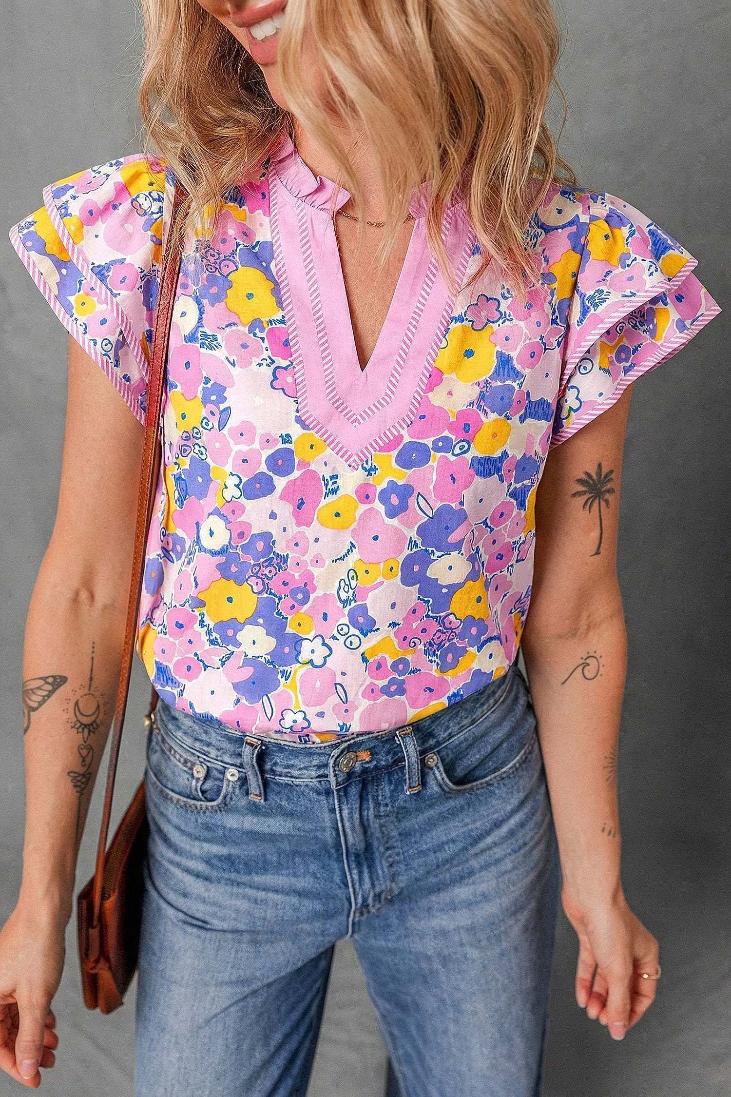 Woman wearing floral print striped color block patchwork blouse with V-neck and flutter sleeves