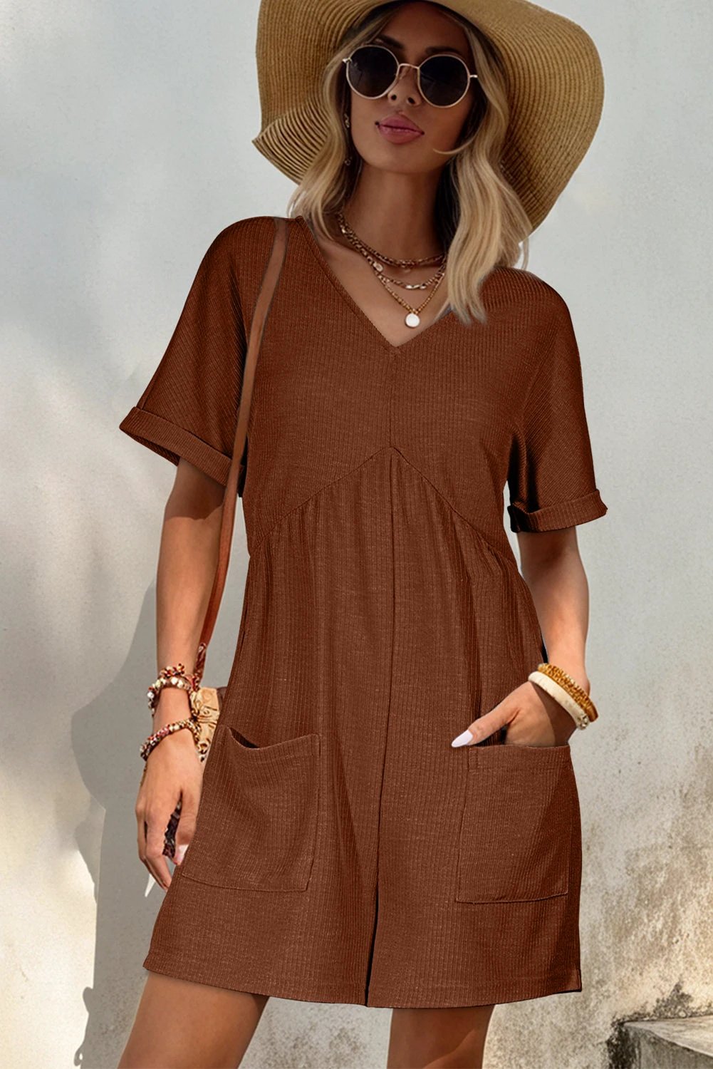 Woman wearing coffee solid color knit V-neck zip romper with front pockets and ribbed texture