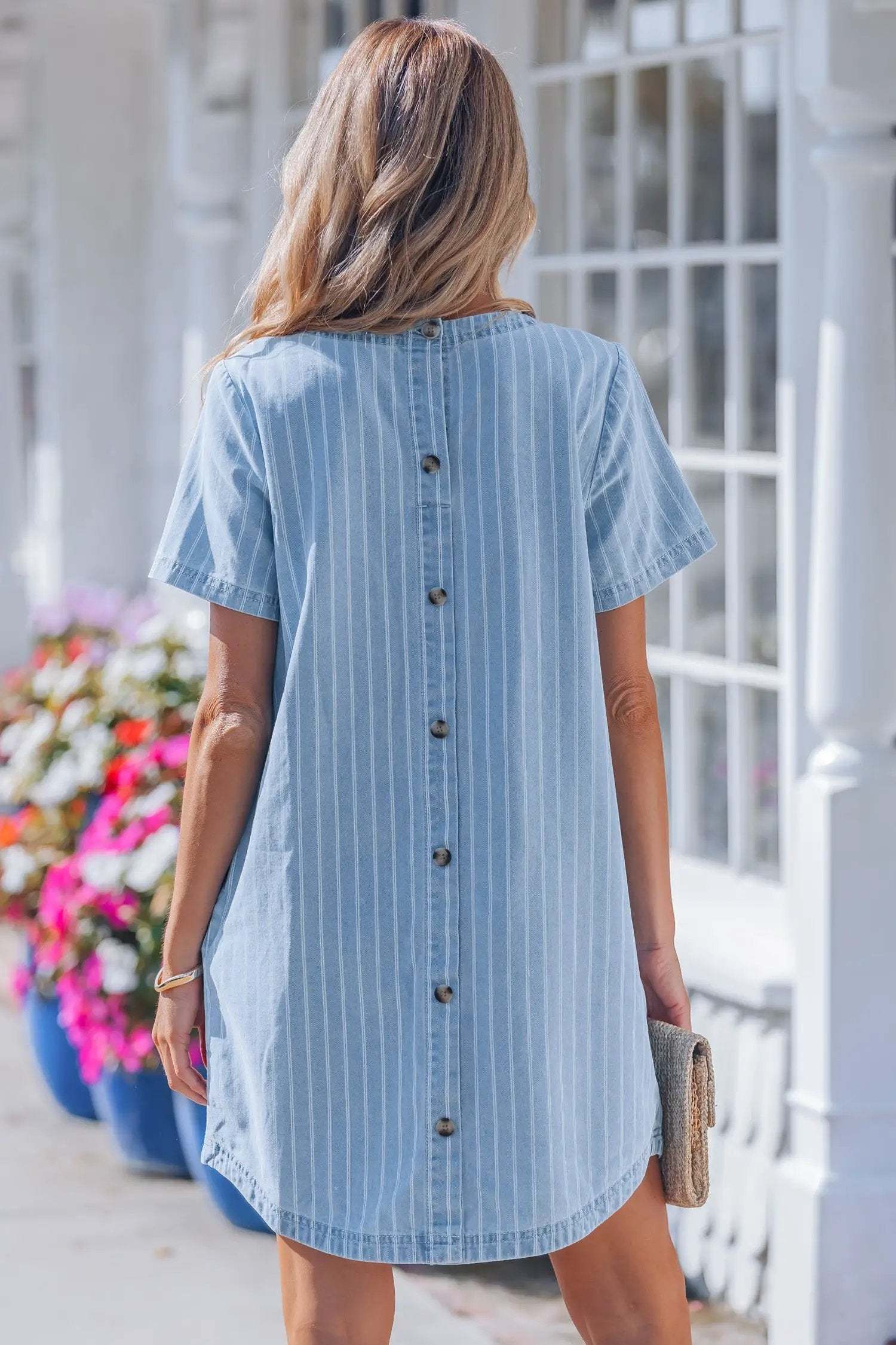 Woman wearing a stripe denim mini dress with buttoned back in casual setting
