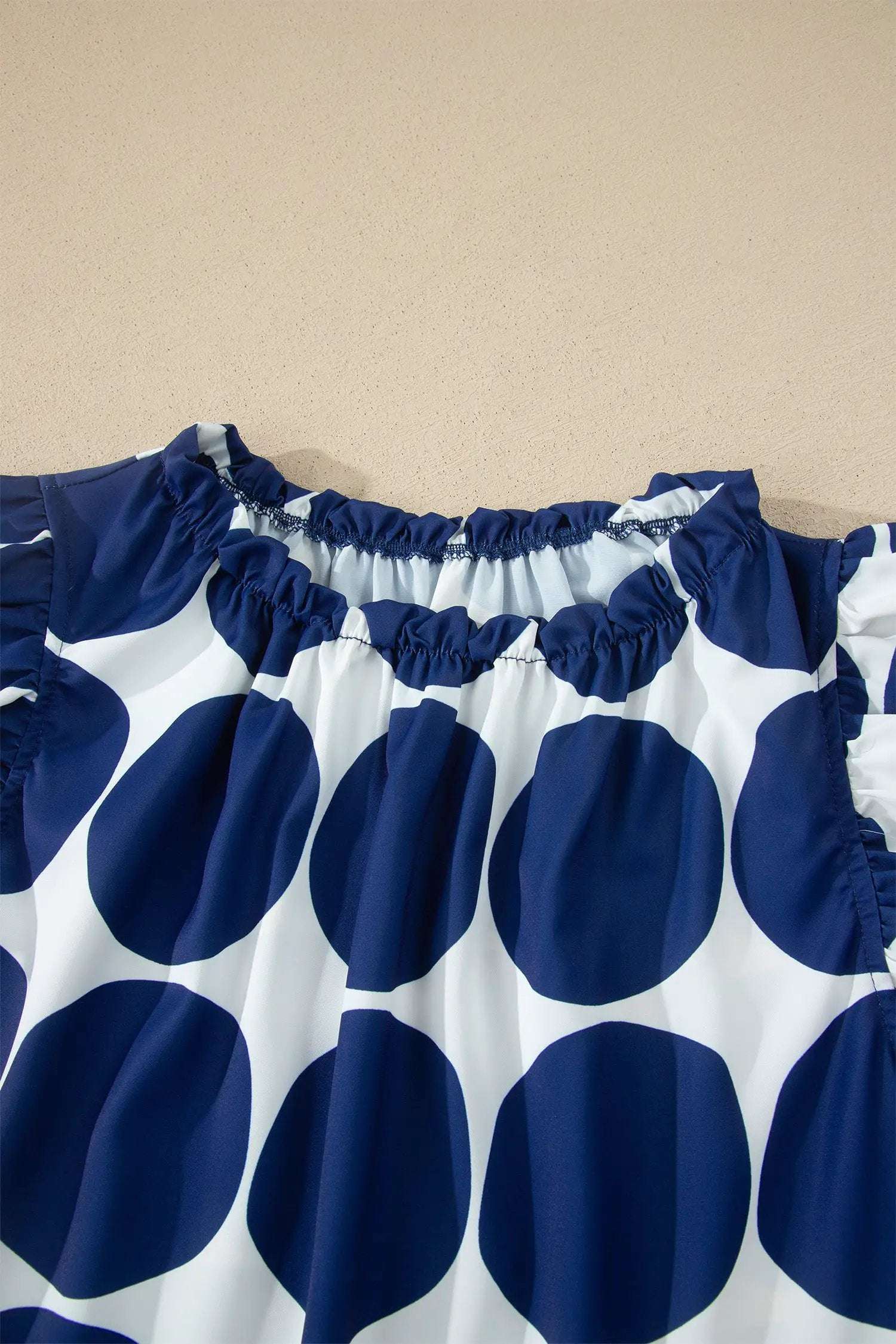 Blue and white polka dot tank top with frilled round neckline and sleeveless design