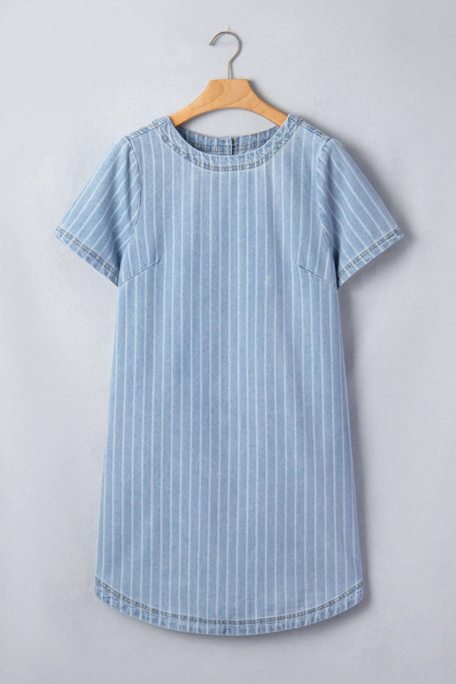 woman wearing stripe denim mini dress with buttoned back and vertical stripes standing outdoors