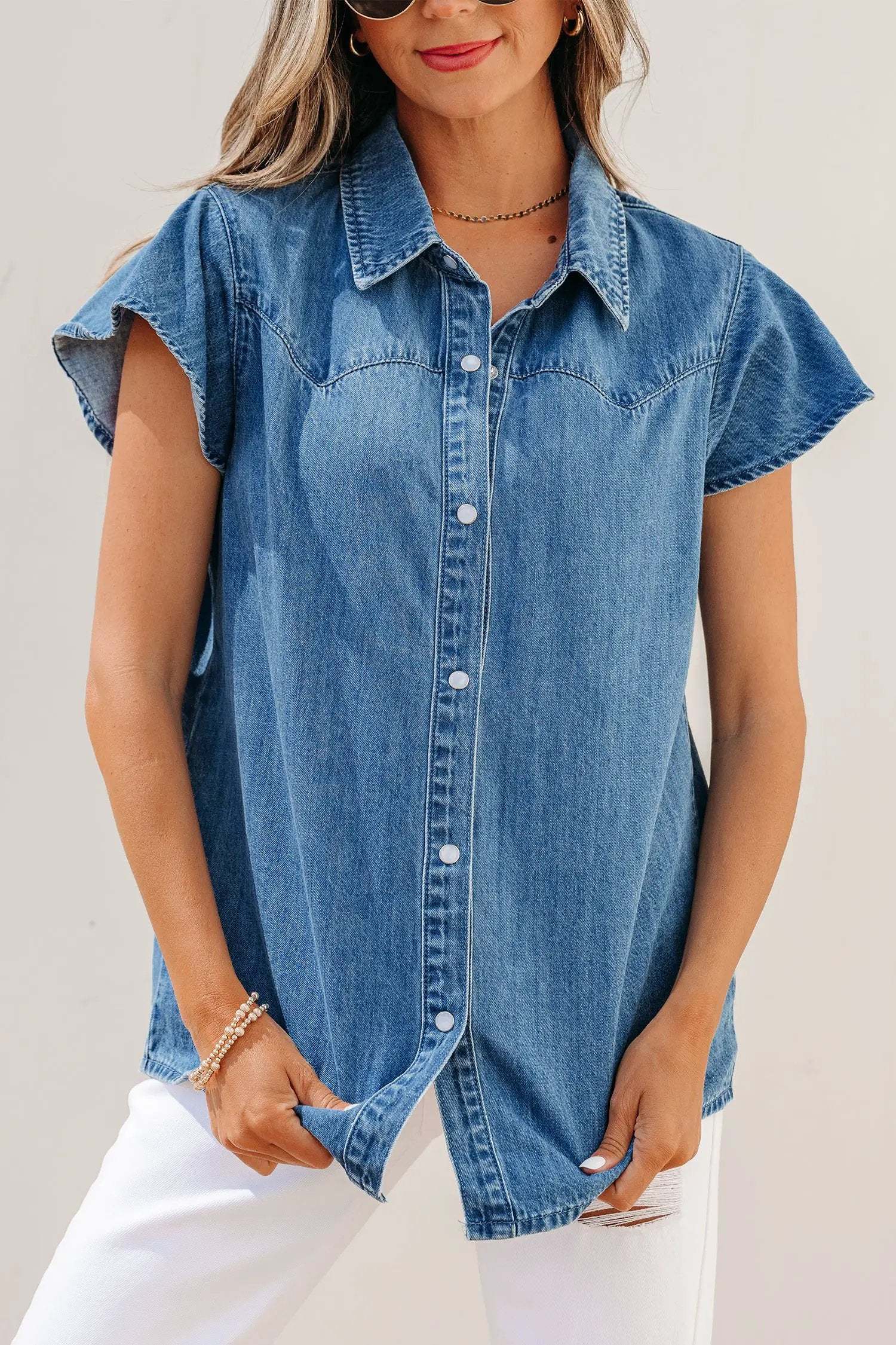Woman wearing denim ruffled short sleeve shirt with button front in casual Western style