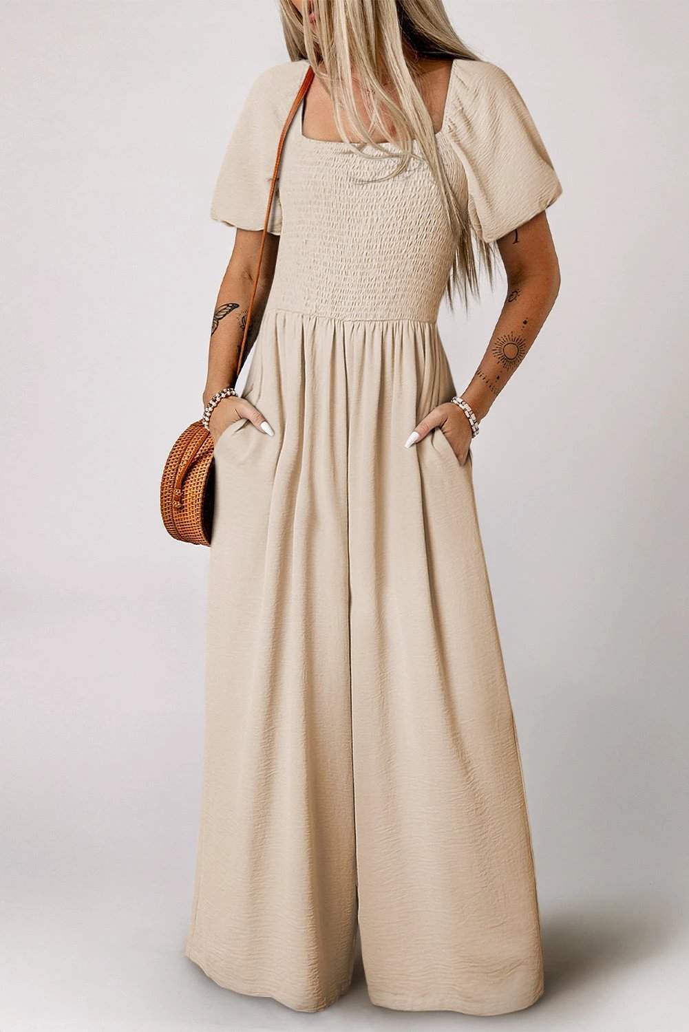 Woman wearing a bubble sleeve smocked wide-leg jumpsuit with square neckline and flowy pants