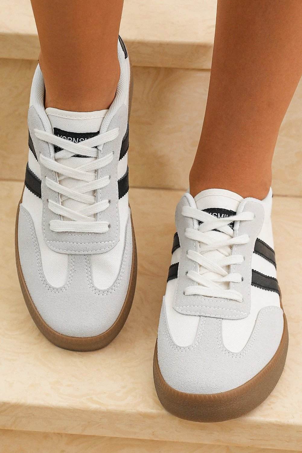 White striped lace-up flat sneakers with black accents for chic mom energy style