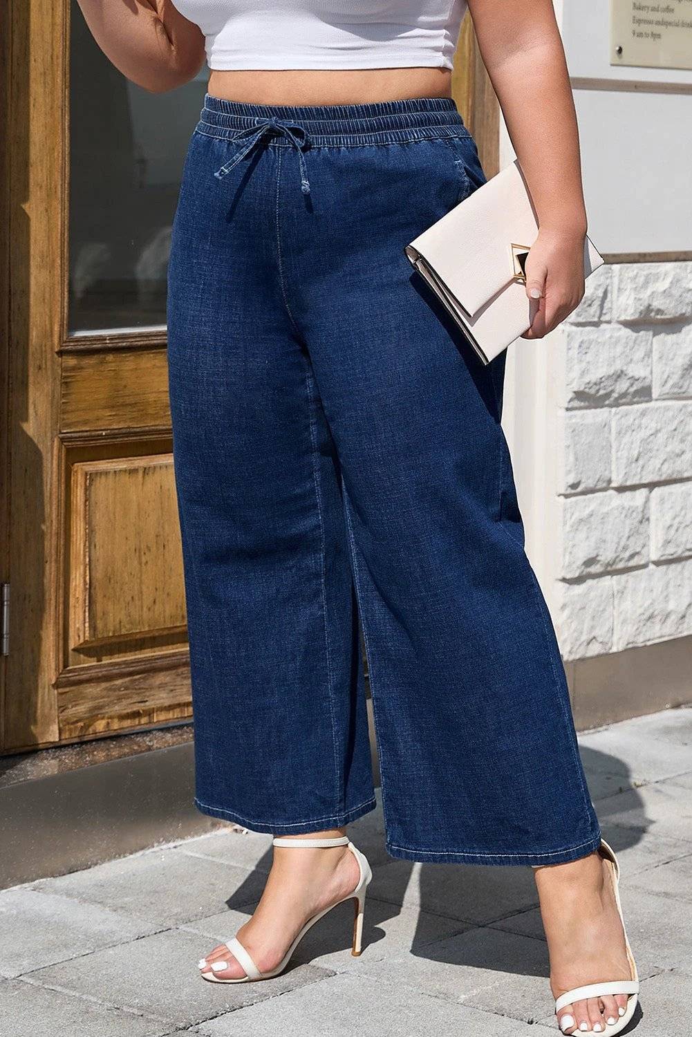 Plus size woman wearing indigo drawstring high waist wide leg jeans standing confidently