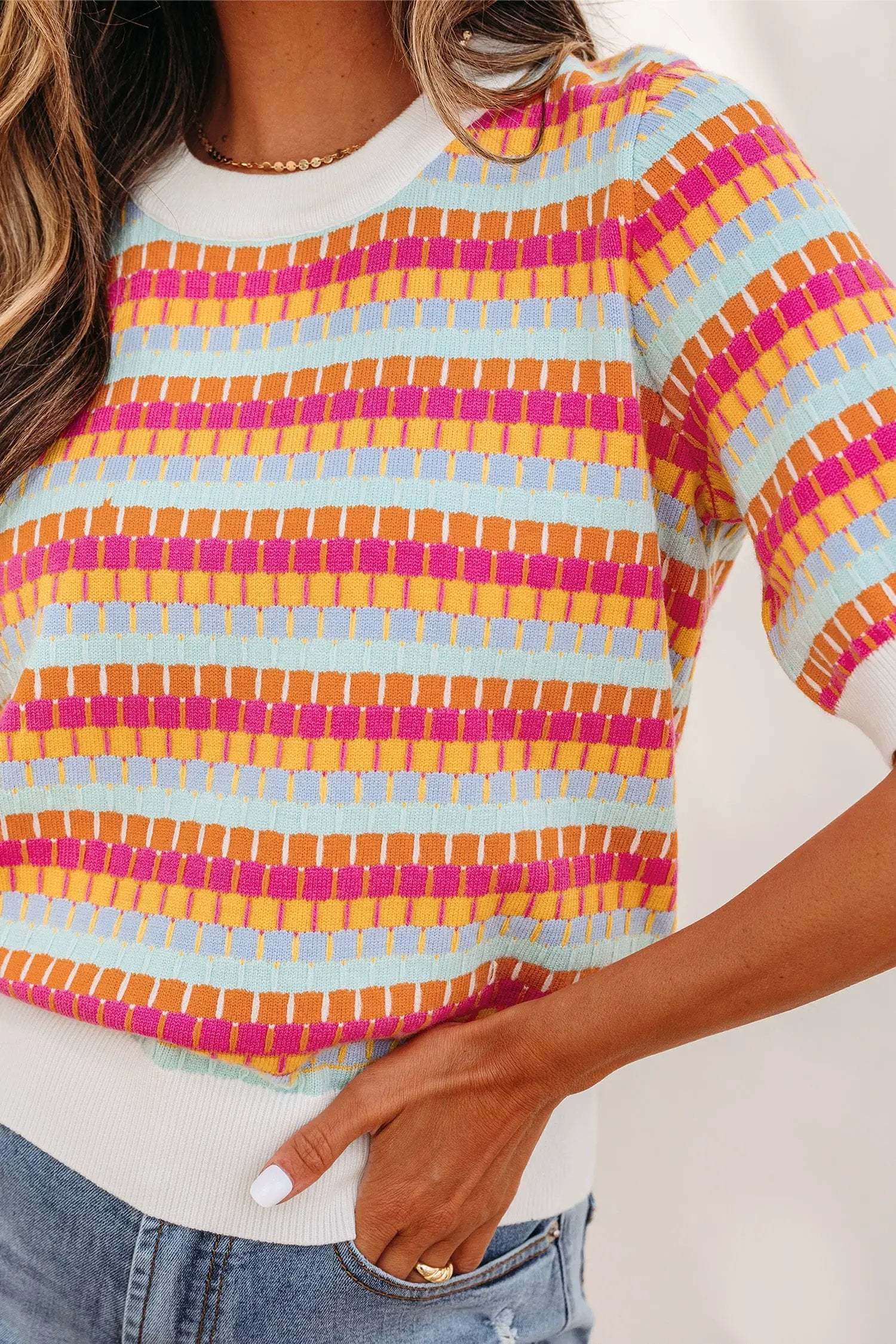 Orange striped knit sweater with abstract stripes and contrasting pink ribbed neckline and cuffs