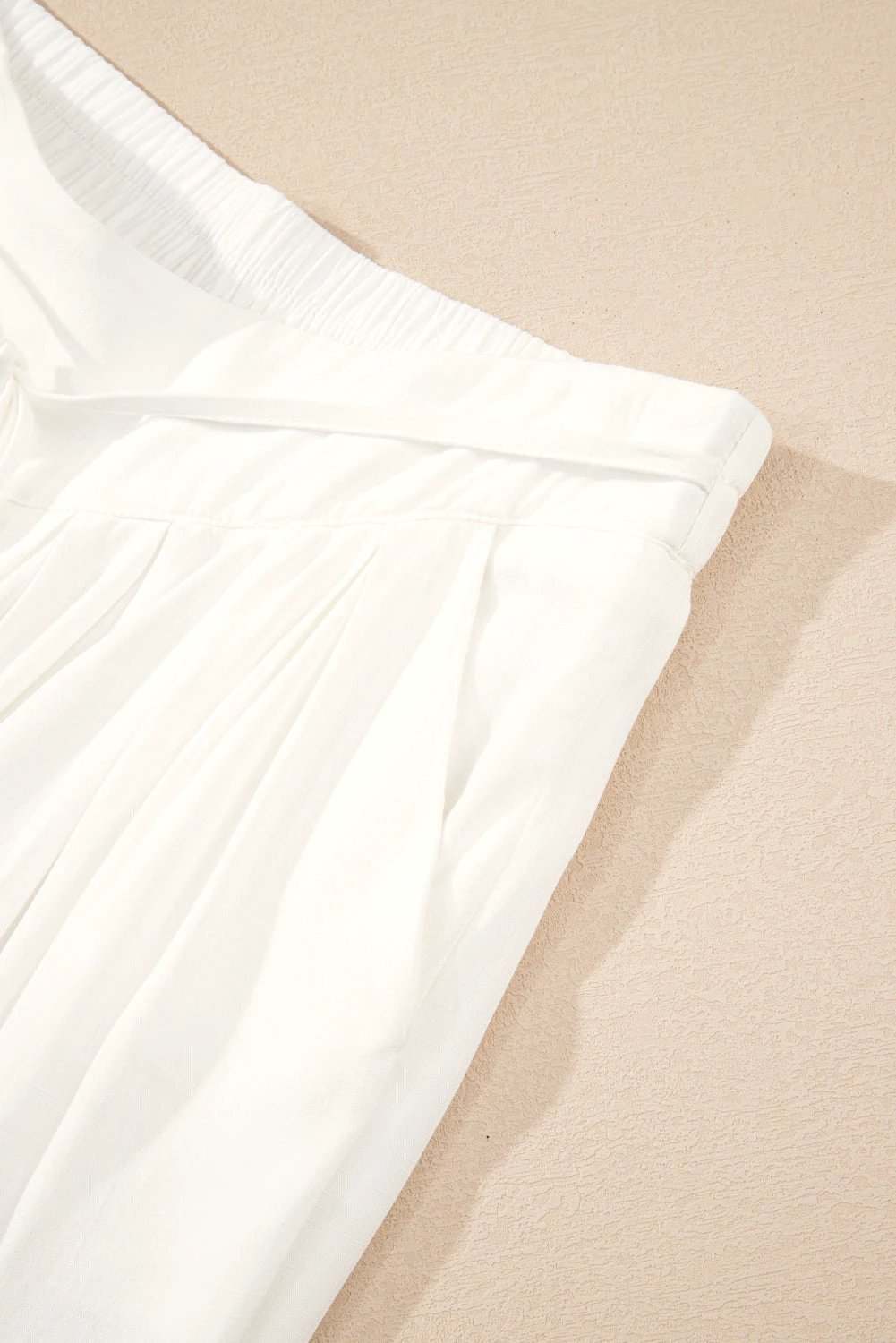 Crisp white drop-waist pleated wide-leg cotton-linen pants with adjustable drawstring waistband and side pockets