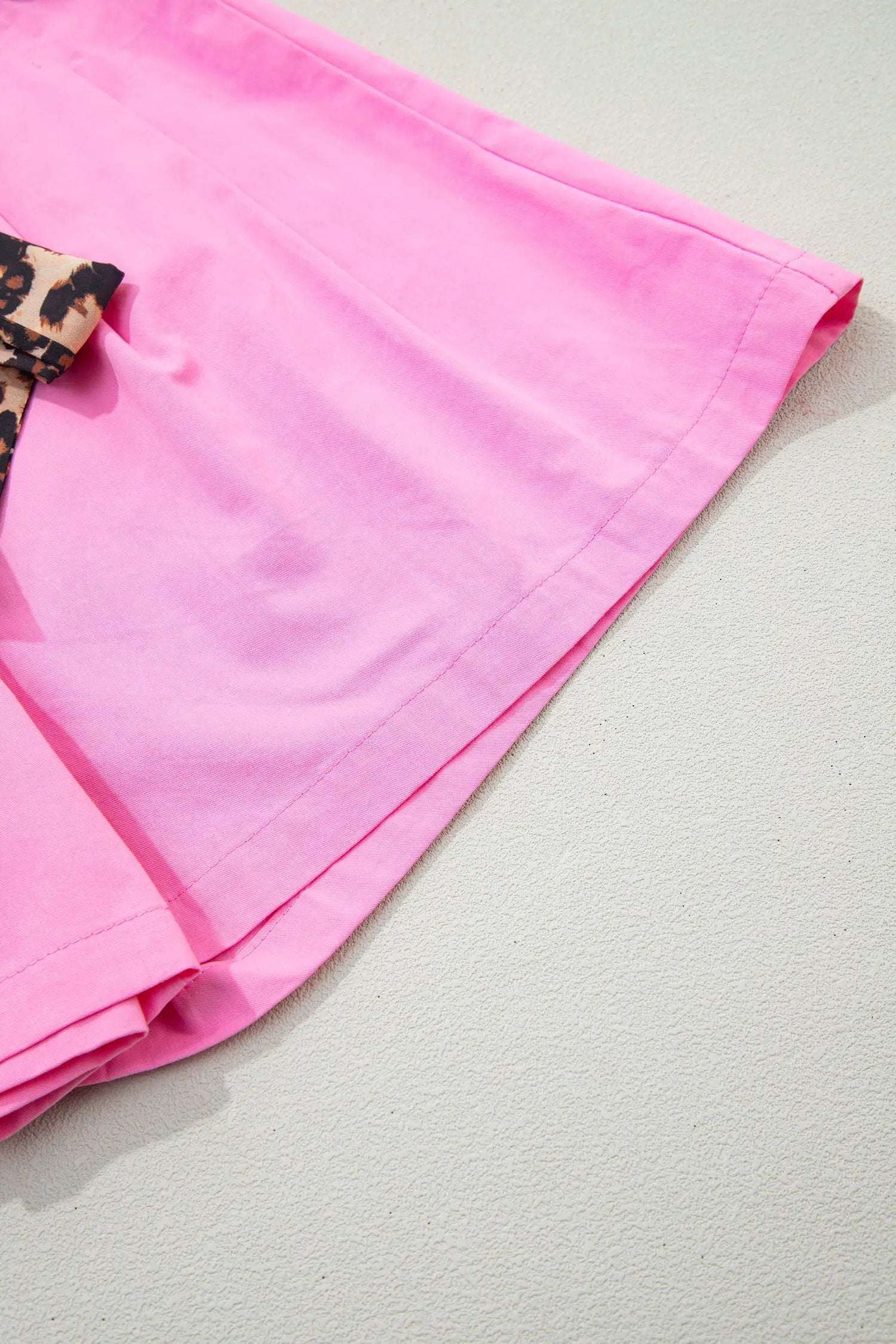 Pink pleated wide-leg shorts with leopard contrast sash belt, styled for casual weekend wear