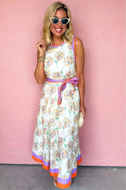 White floral print maxi dress with belted waist and color block trim in a garden setting