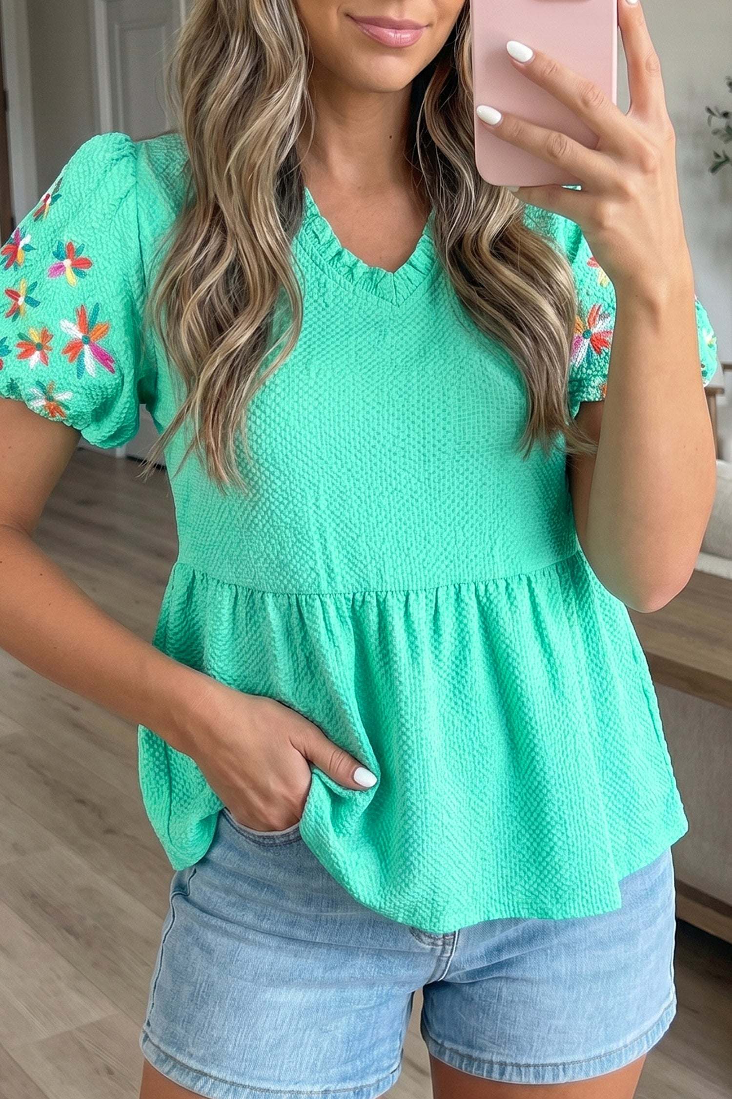 Woman wearing floral embroidered blouse with V-neck and puff sleeves