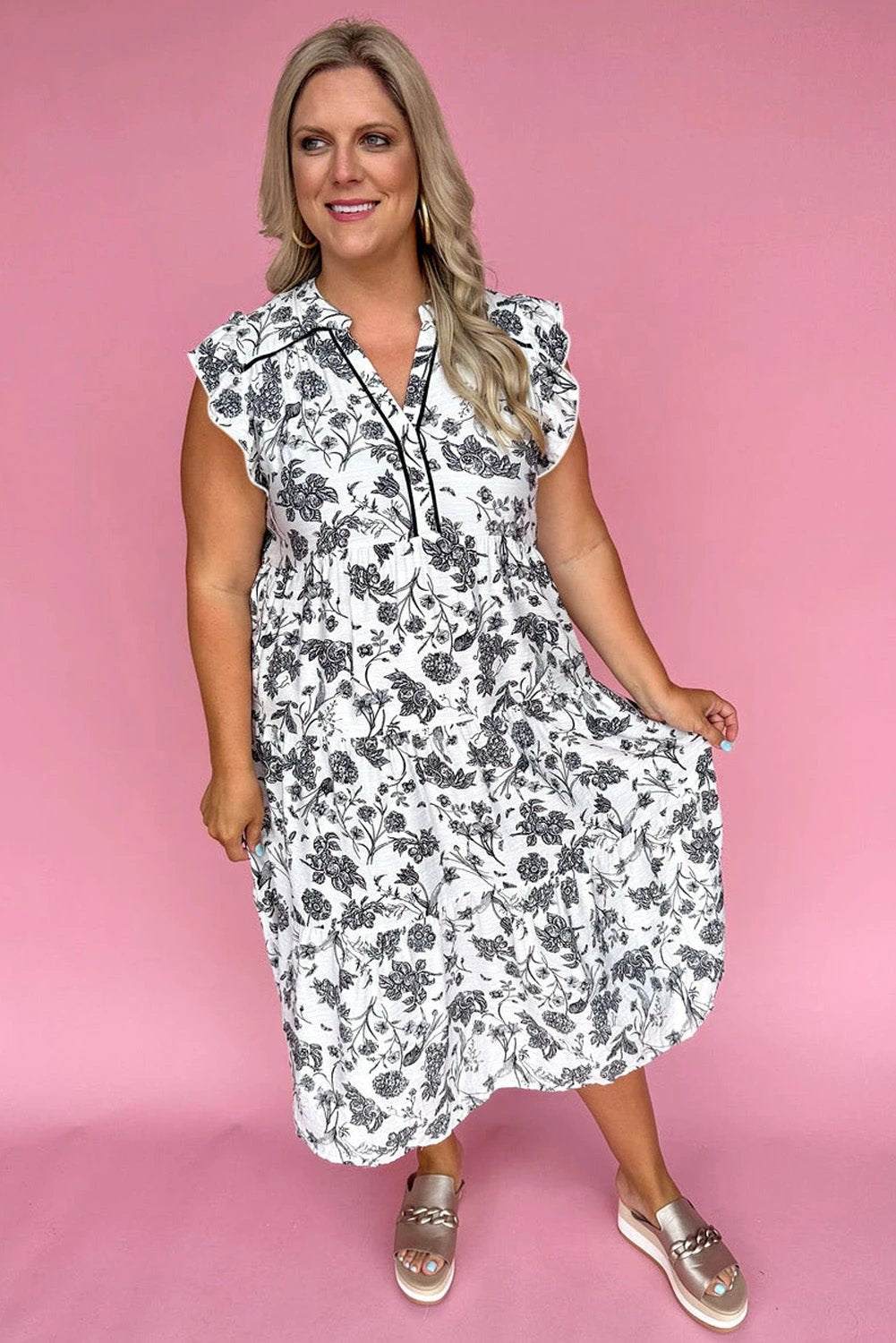 Plus size floral maxi dress with notched neck, piping trim, and ruffle sleeves on a model