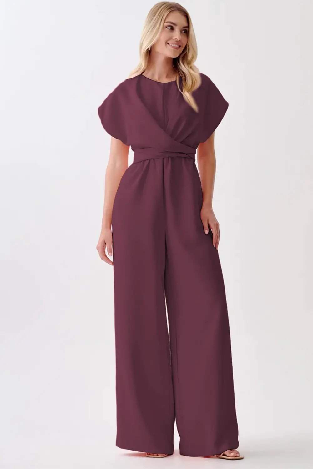 Woman wearing a wine-colored knot-waist cap sleeve jumpsuit with wide-leg silhouette